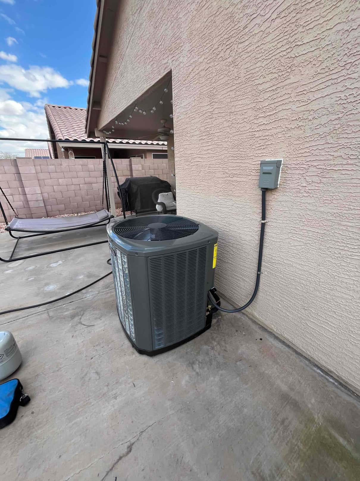New outdoor condenser set on a level pad with electrical disconnect mounted and refrigerant line set connected to the unit.