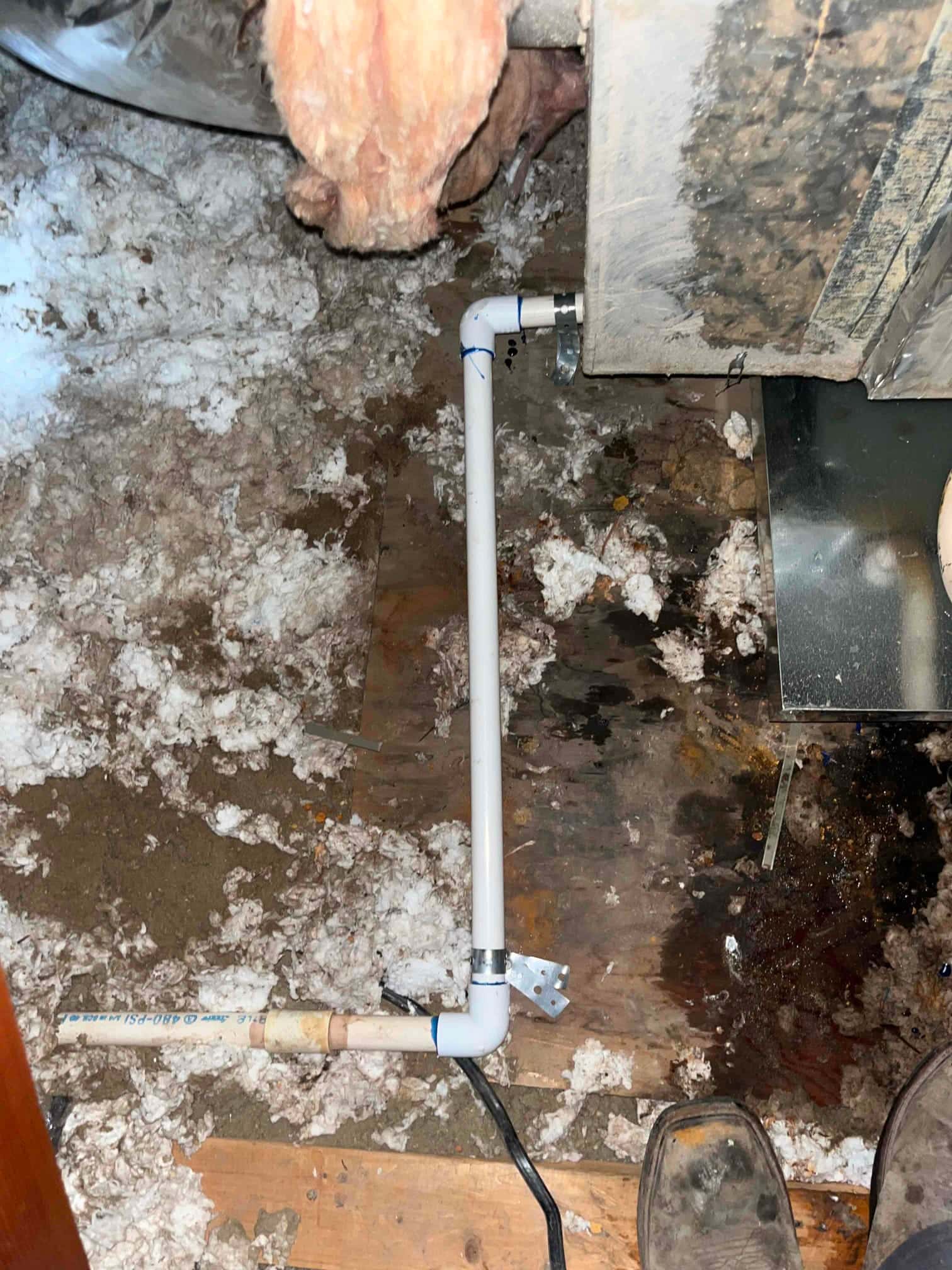 New PVC condensate drain line installed at the air handler, with fittings and support bracket secured above the floor.