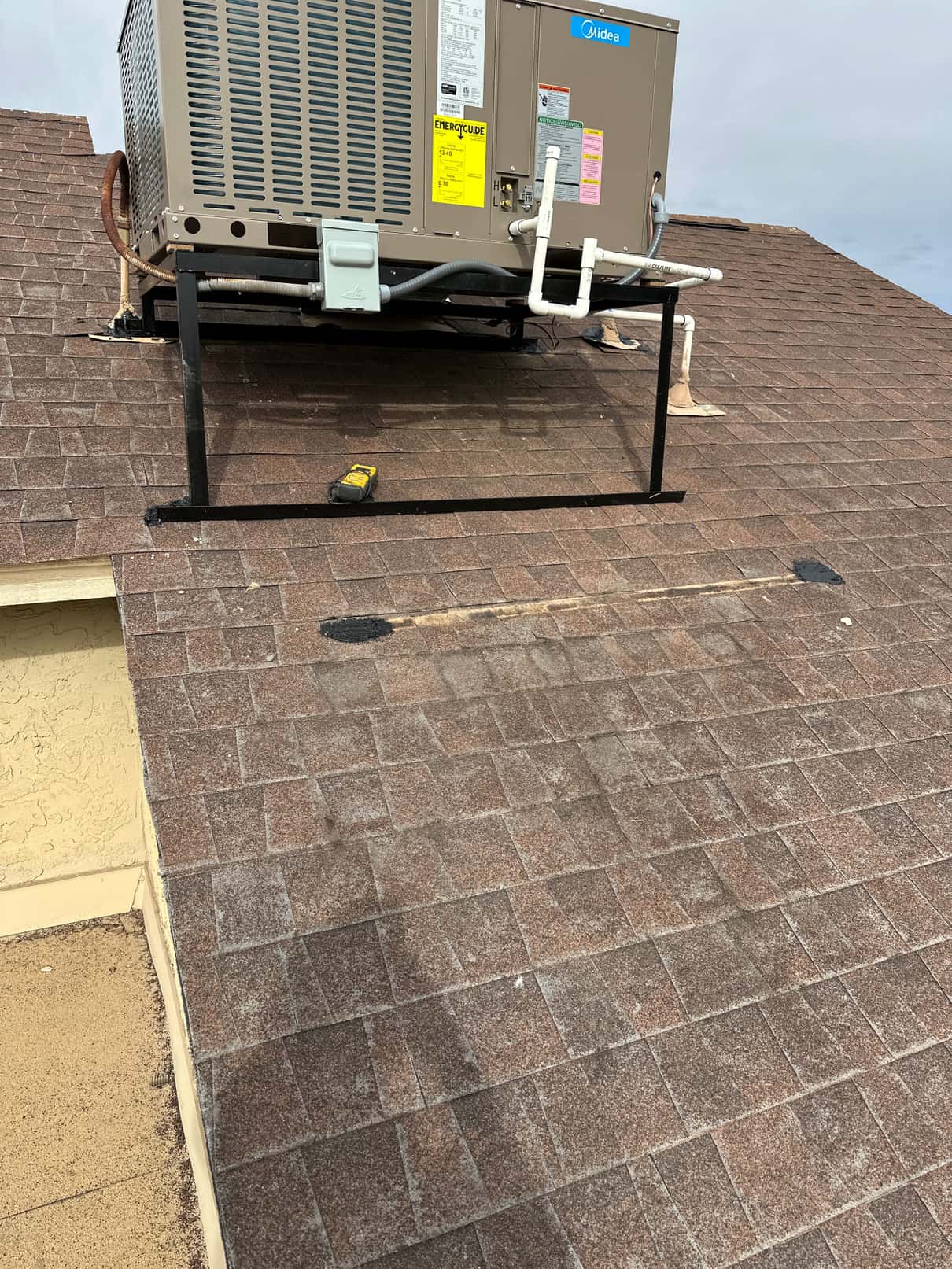 New rooftop package unit mounted on a steel stand with electrical whip, disconnect, and condensate drain piping completed.