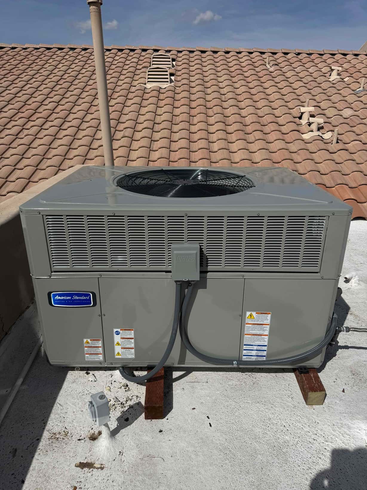 New rooftop package unit set on risers with flexible electrical whip and disconnect box installed, ready for commissioning.