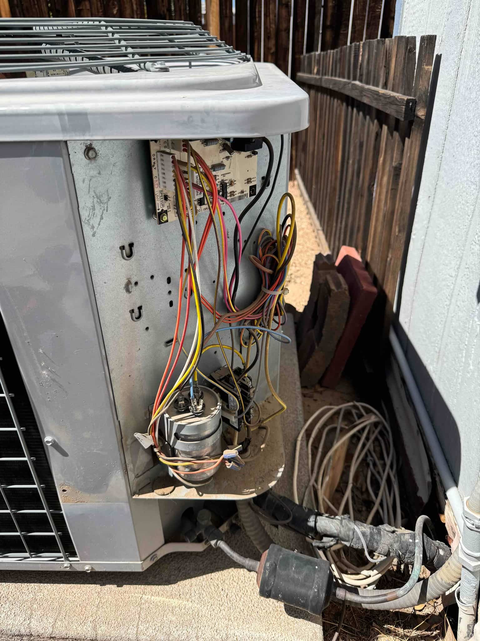 Open condenser control compartment shows exposed wiring, contactor, and dual-run capacitors mounted in the electrical bay.