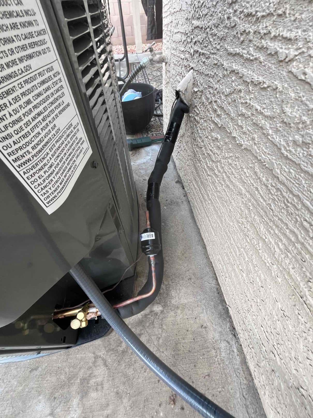 Outdoor condenser with insulated refrigerant line set, sealed wall penetration, and installed liquid-line filter drier at the service connection.