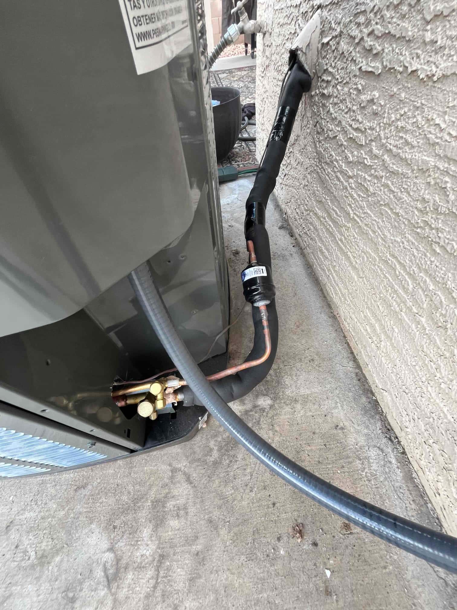 Refrigerant line set routed and insulated into the wall, connected to the outdoor condenser with sealed penetration and service valves accessible.