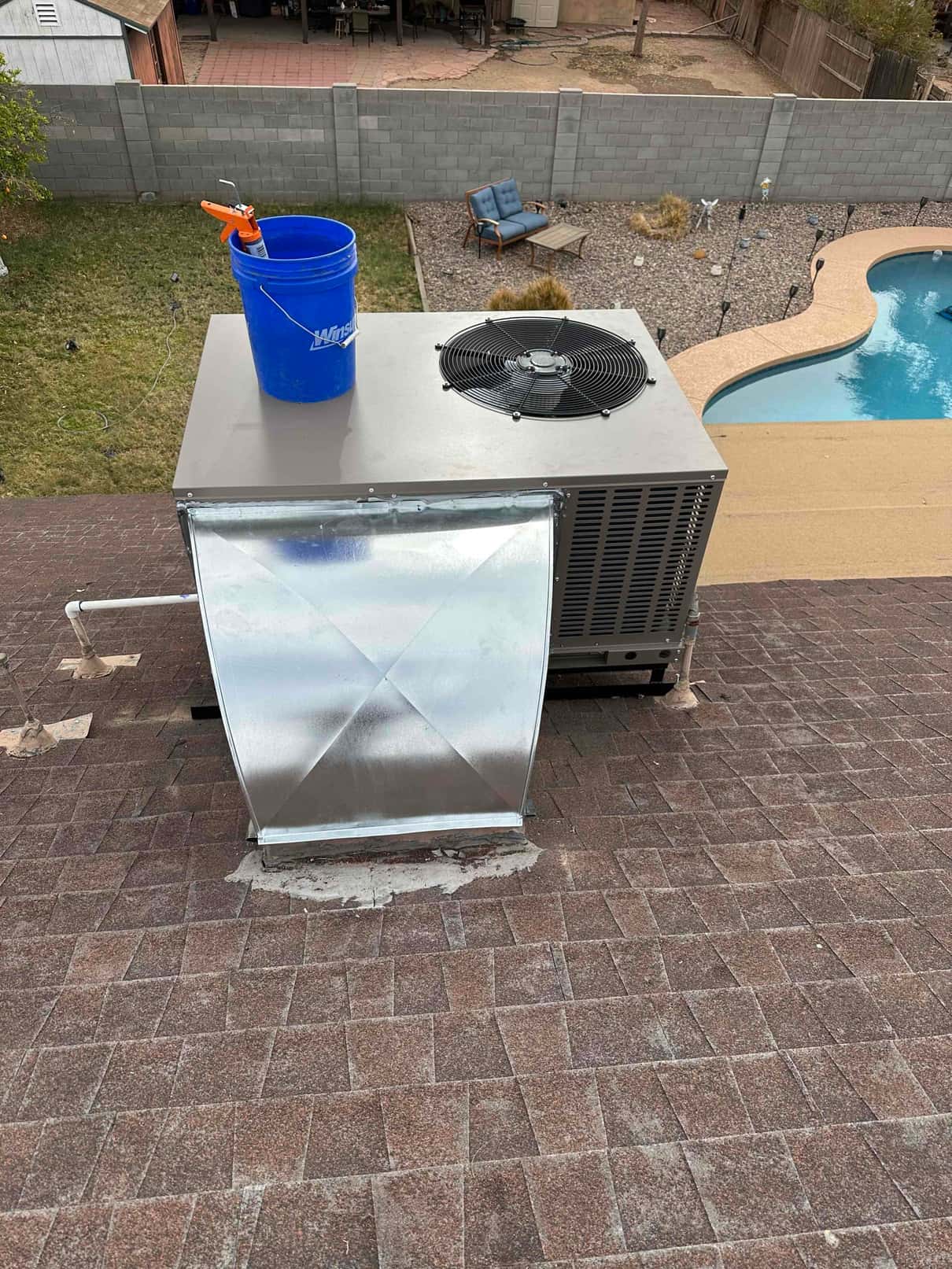 Rooftop package unit newly set with sealed curb and transition duct, condenser fan visible on top during installation.