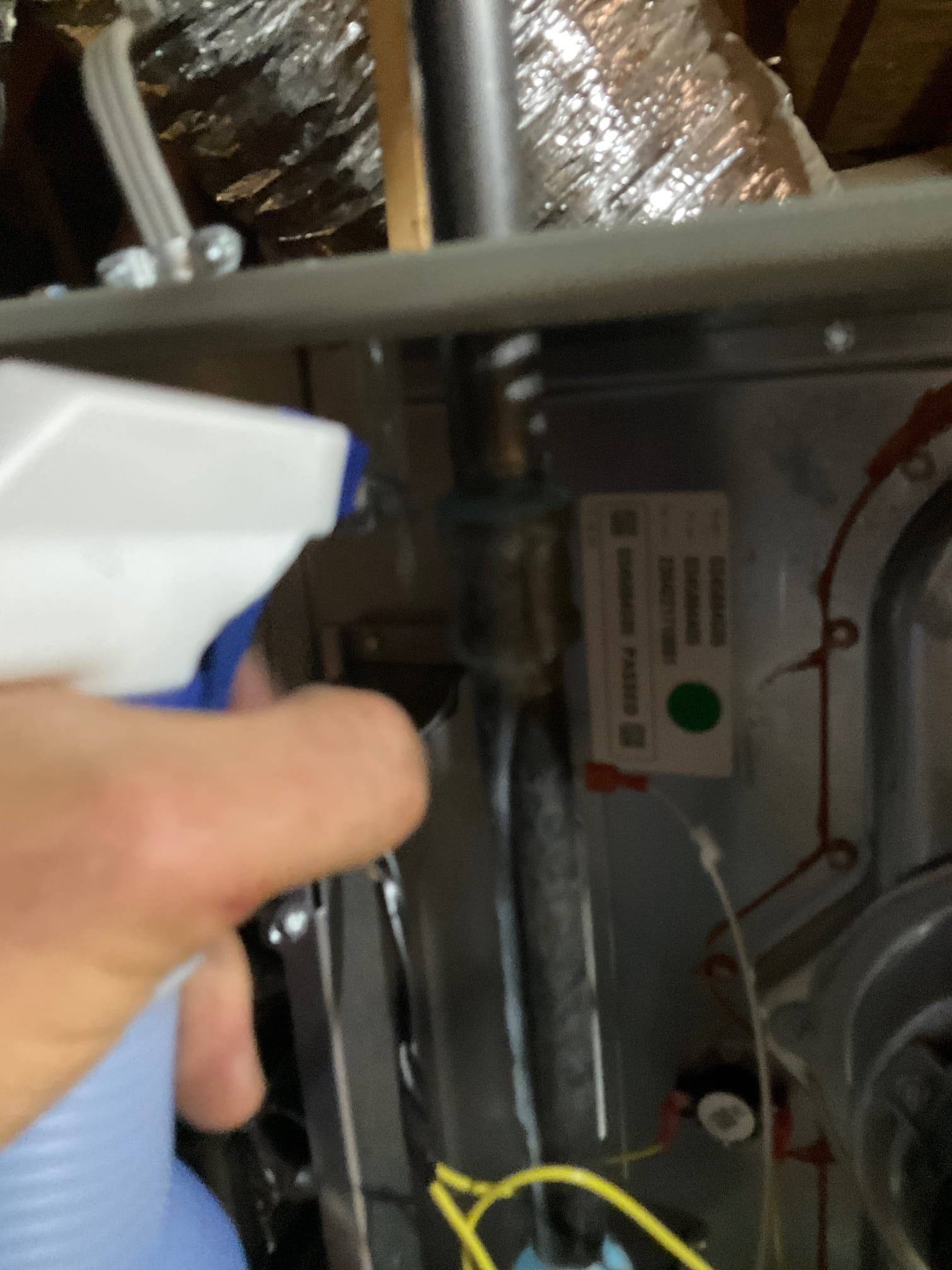 Technician sprays solution on an interior gas line connection inside the furnace cabinet to check for leaks during installation.