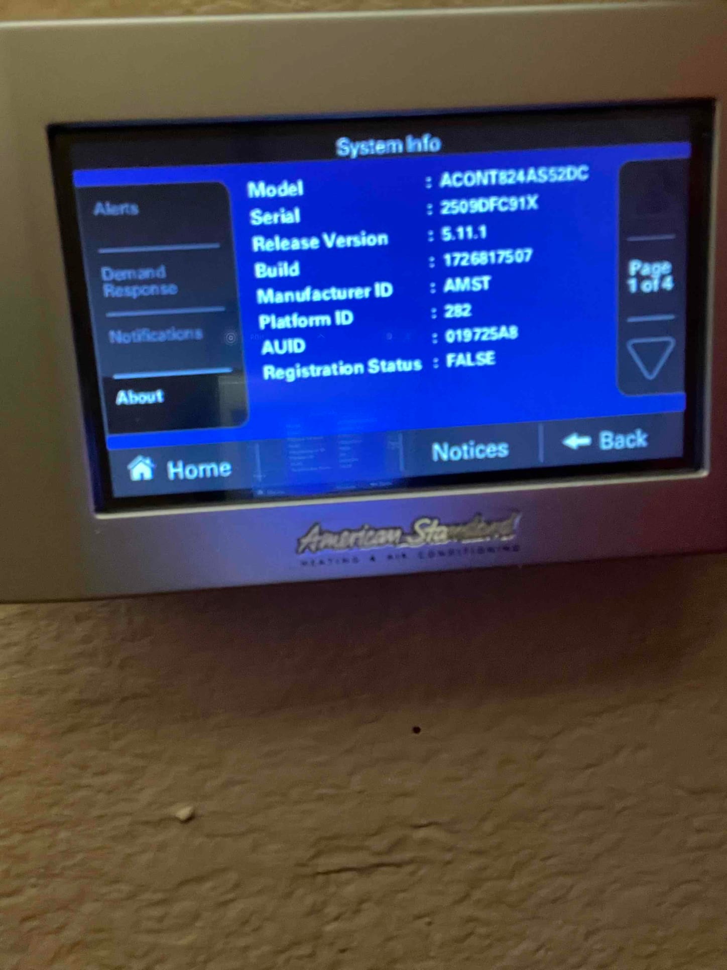 Touchscreen thermostat displaying system information menu on the wall after installation and setup.