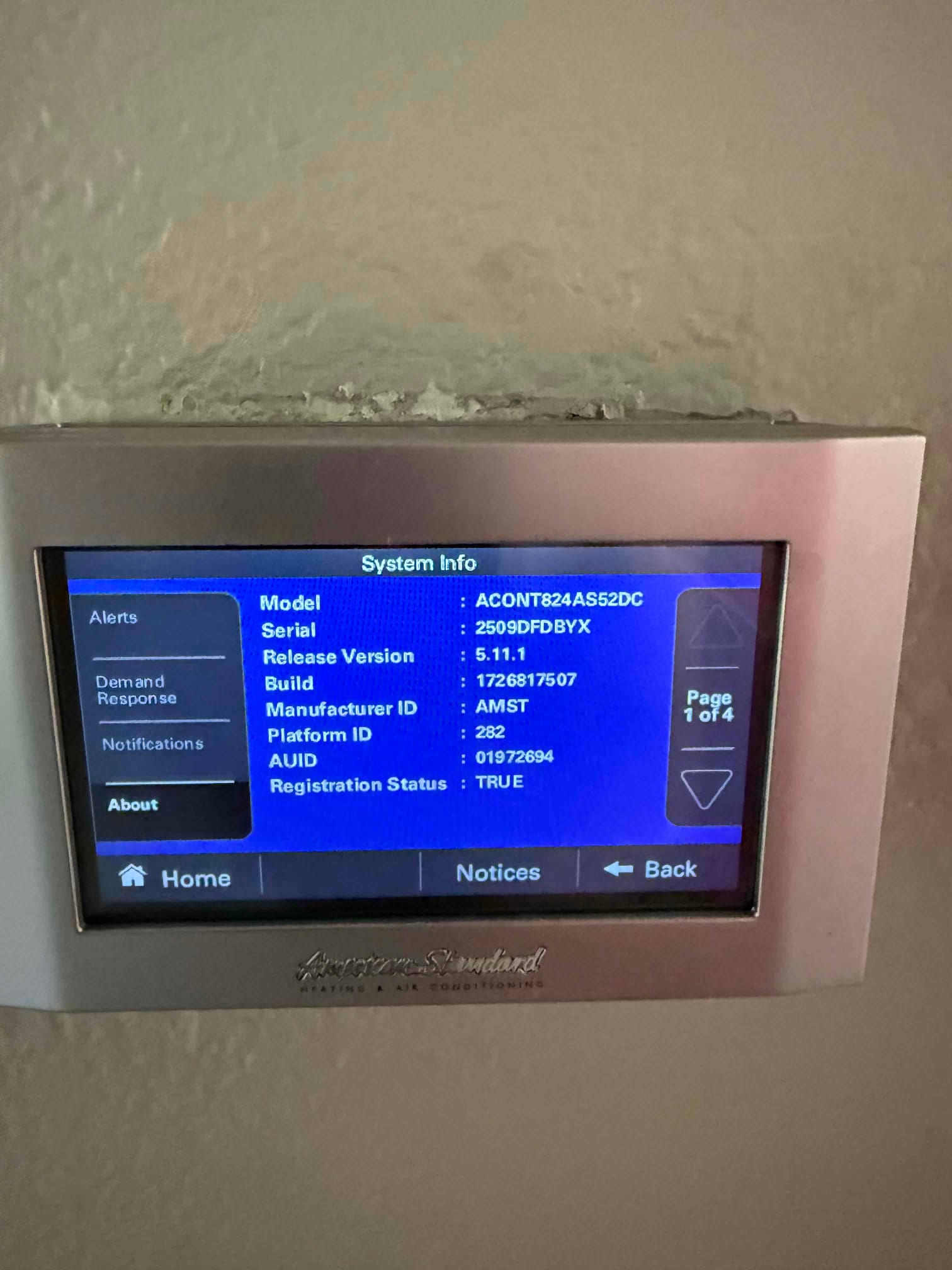 Touchscreen thermostat displays system information menu after installation, confirming communication and registration status on the new control.