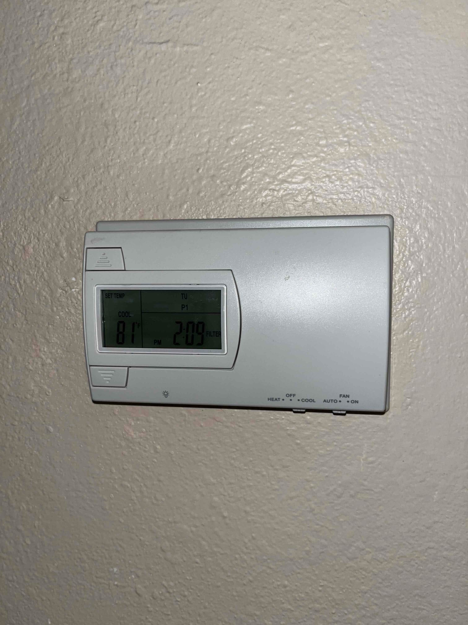 Wall-mounted digital thermostat displays COOL mode with room temperature at 81°F and fan set to AUTO.