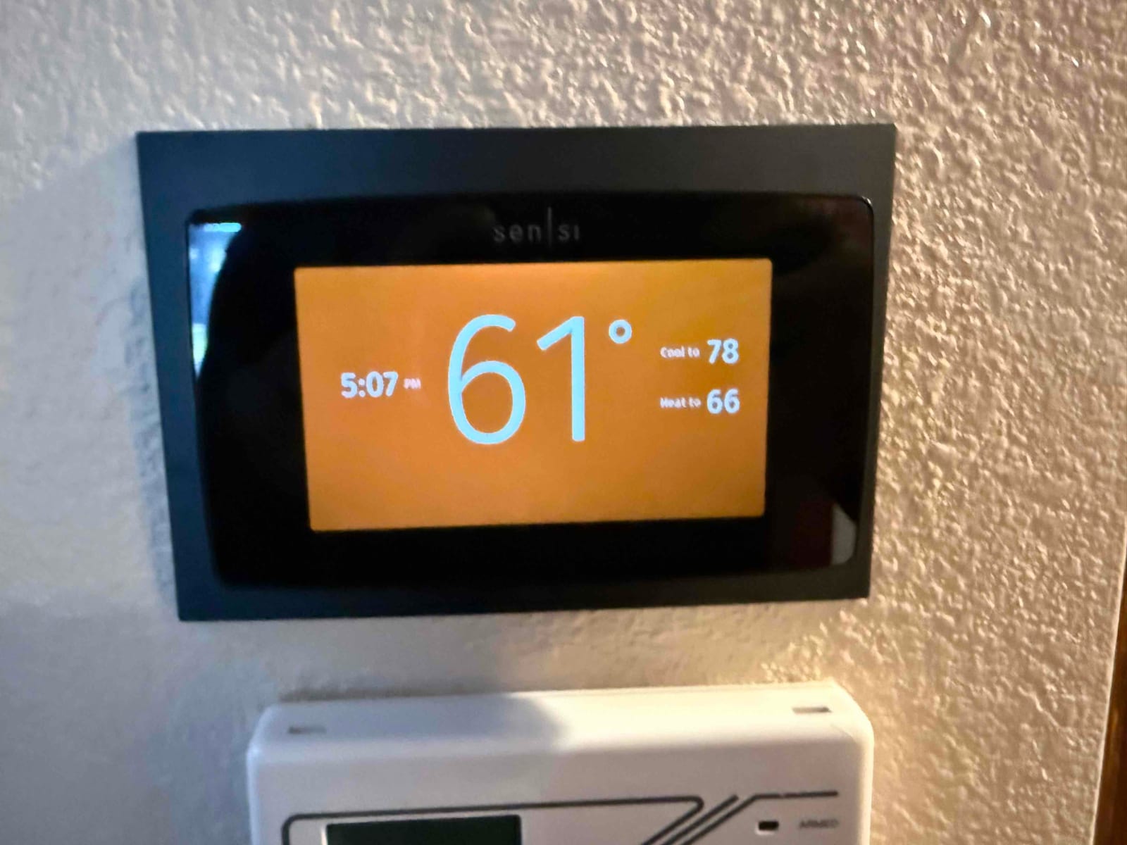 Wall-mounted smart thermostat displays 61 degrees with cooling set to 78 and heating set to 66.