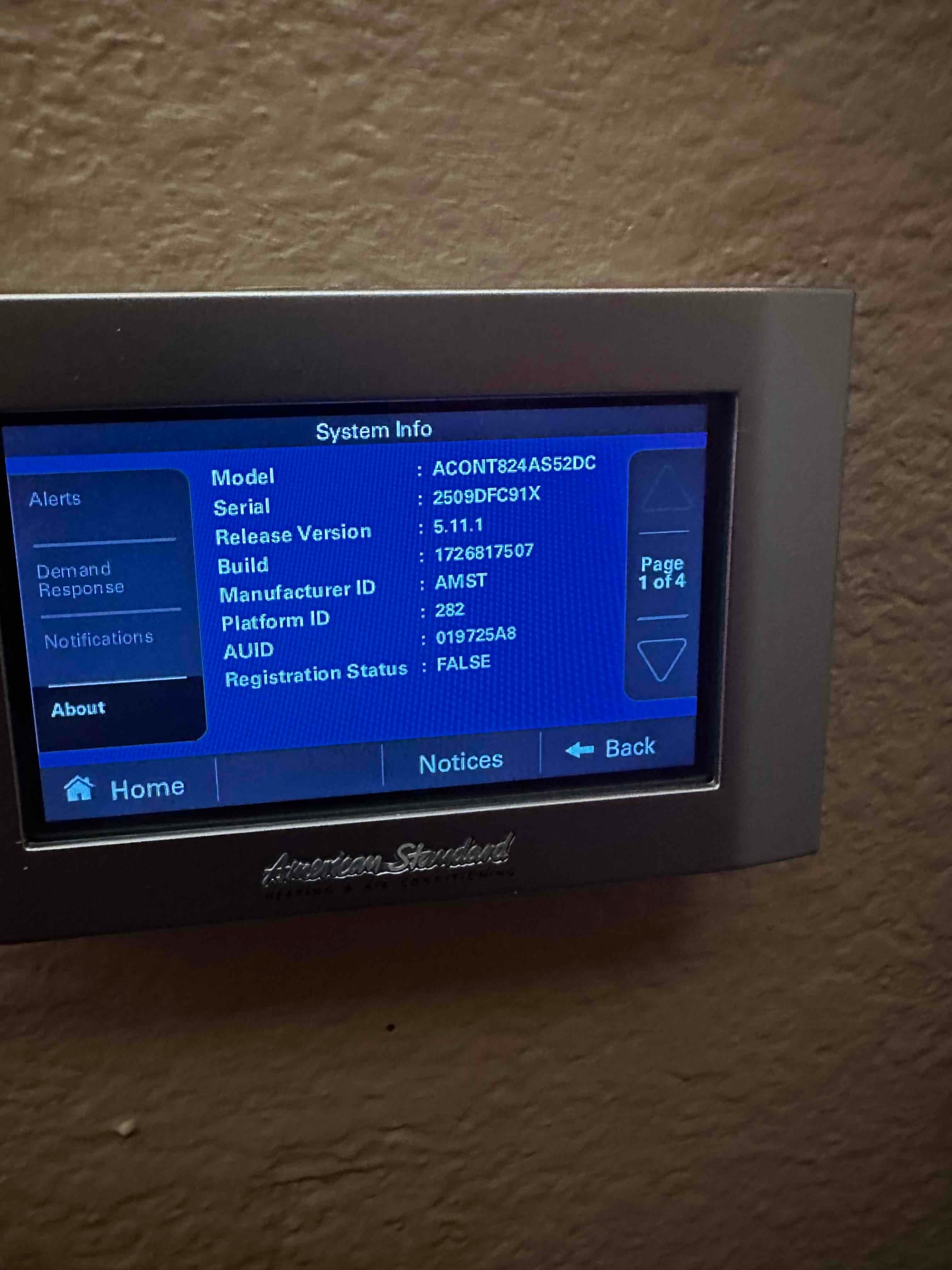 Wall-mounted touchscreen thermostat displays system information menu during setup at a newly installed HVAC system.
