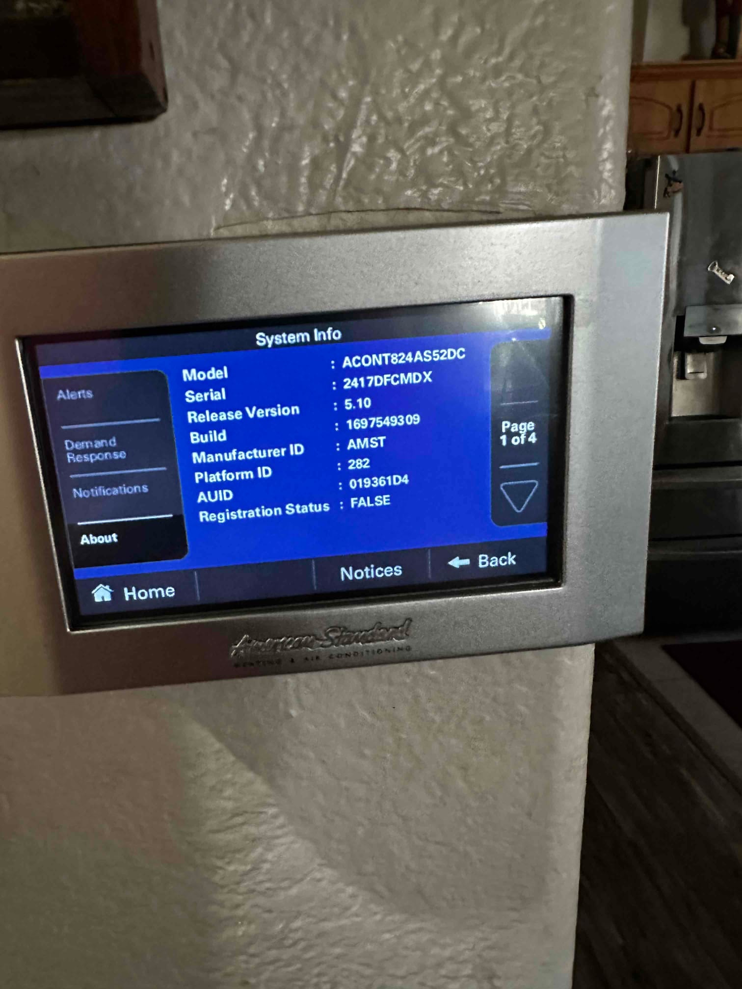 Wall-mounted touchscreen thermostat displays system information menu after installation and setup.