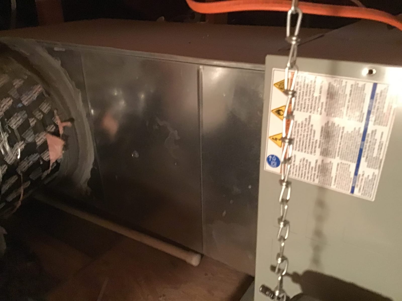 Air handler cabinet in attic with sheet metal plenum, insulated flex duct connection, and PVC condensate drain visible.