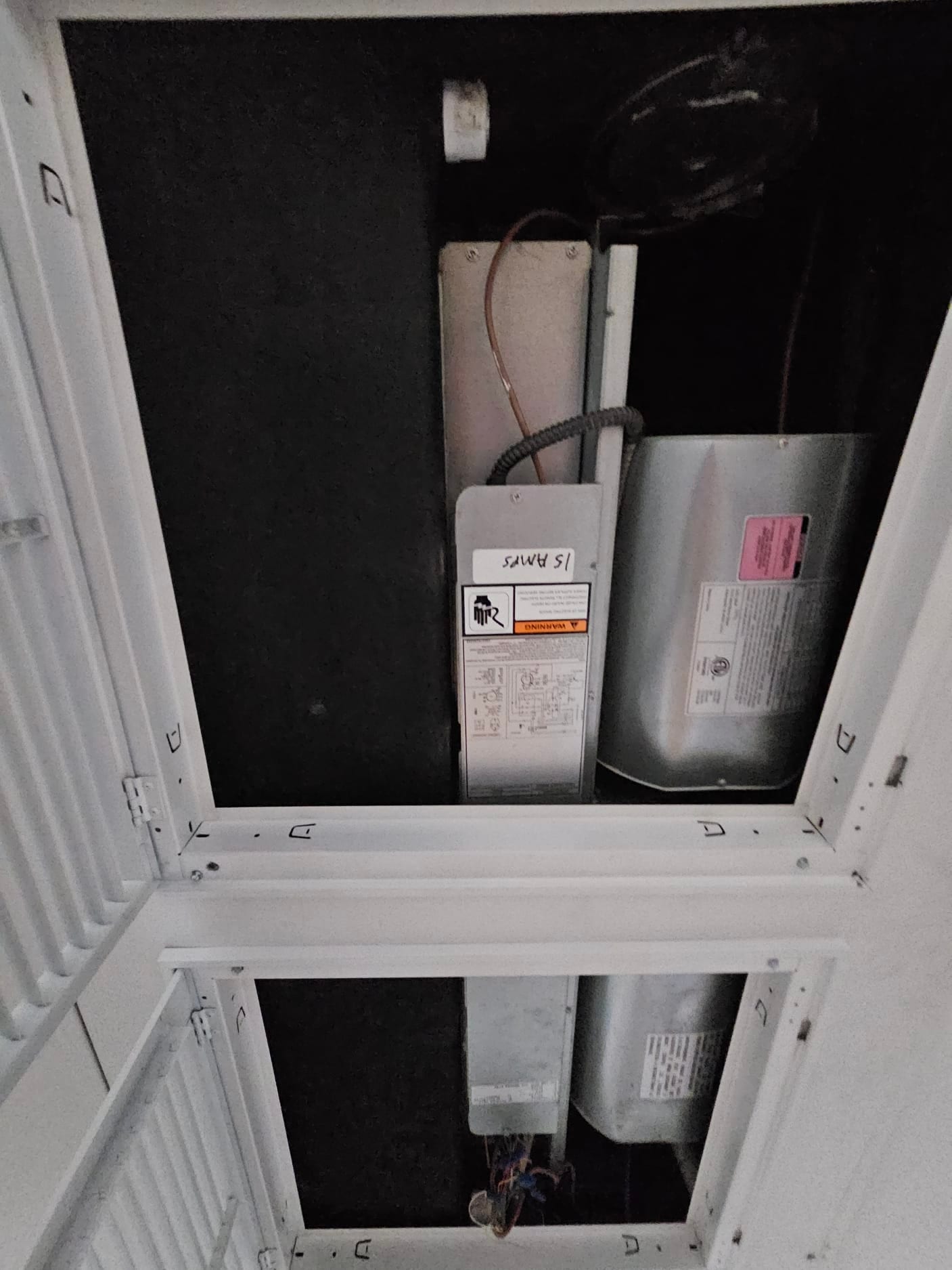 Ceiling-mounted air handler compartment open, showing blower housings, wiring, and access panels with warning labels.