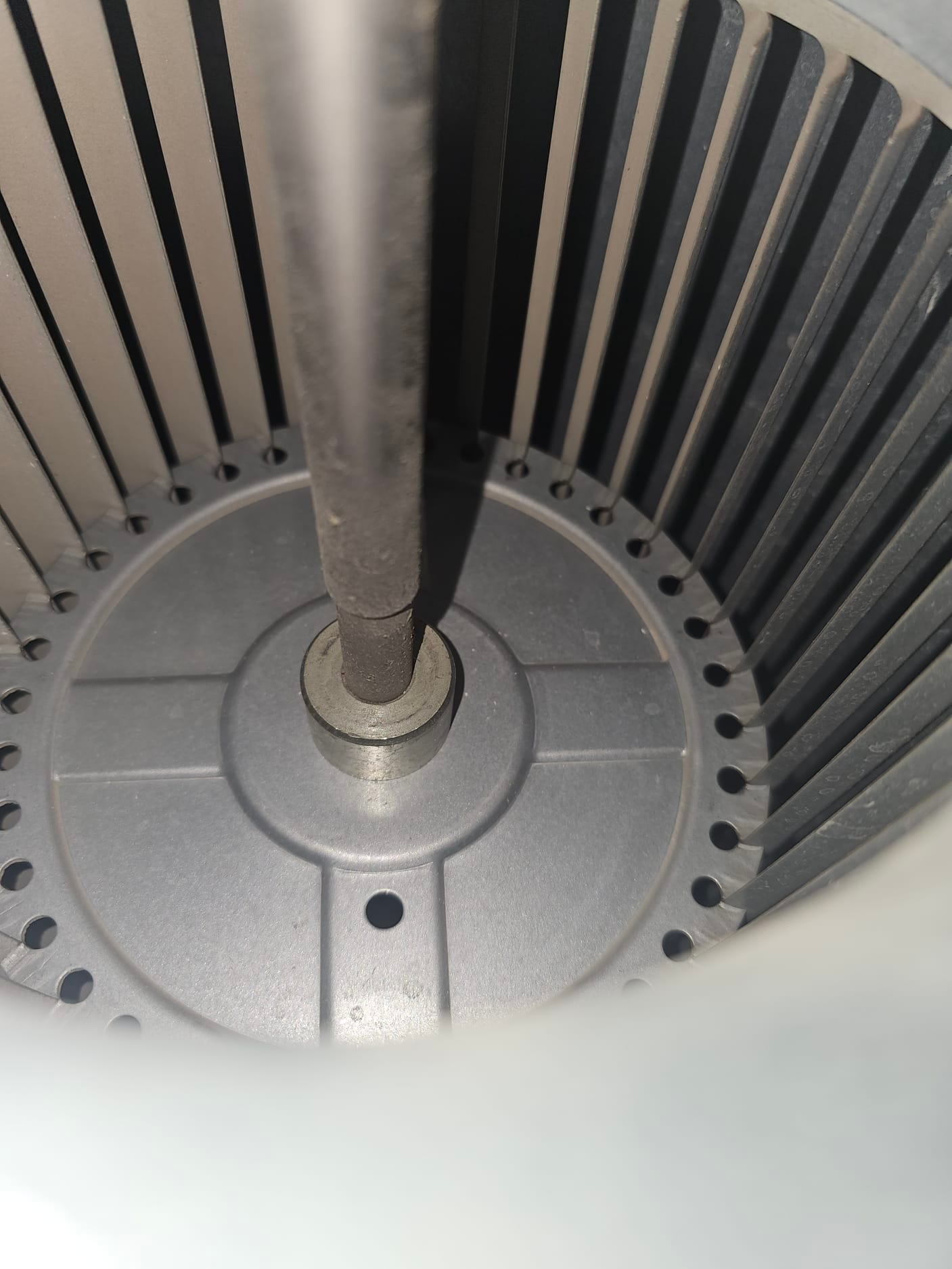 Centrifugal blower wheel showing the motor shaft and hub, with straight fins around the circular housing interior.