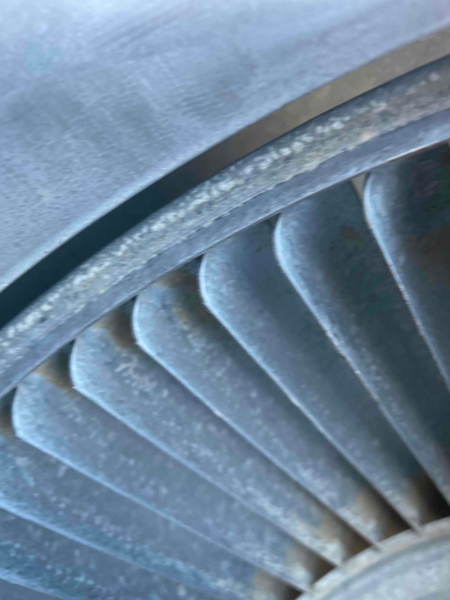 Close-up of axial fan blades inside a round metal shroud, showing light dust on blade edges.