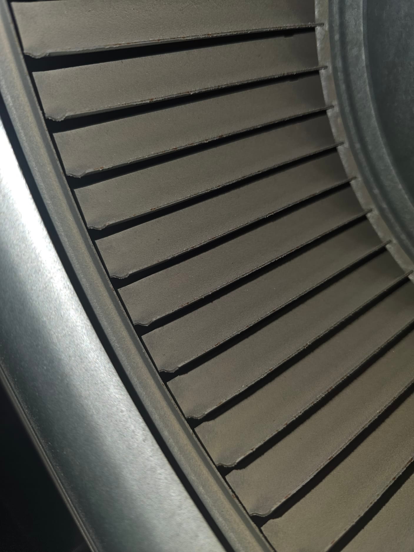 Close-up of HVAC blower wheel, showing the curved metal blades and circular housing rim inside the unit.