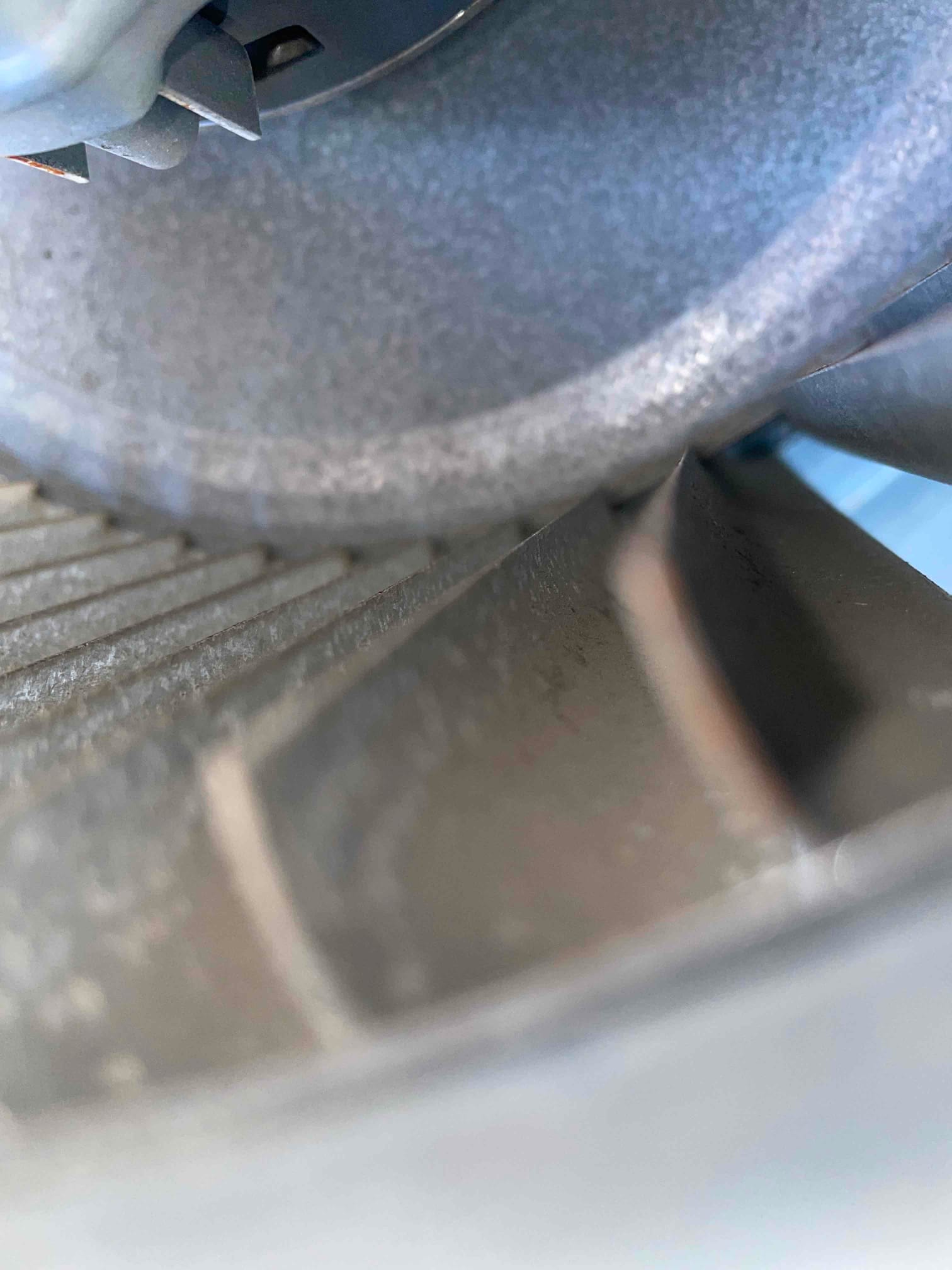 Close-up of metal fan blades and surrounding housing inside an HVAC unit cabinet.