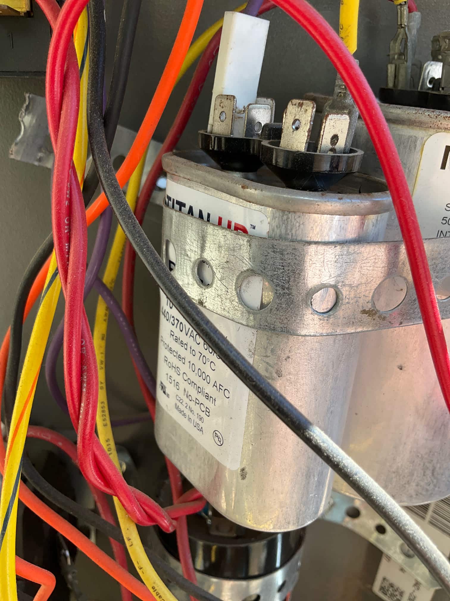 Dual-run capacitor with connected wiring inside the condenser control compartment, labeled 440/370 VAC and rated to 70°C.