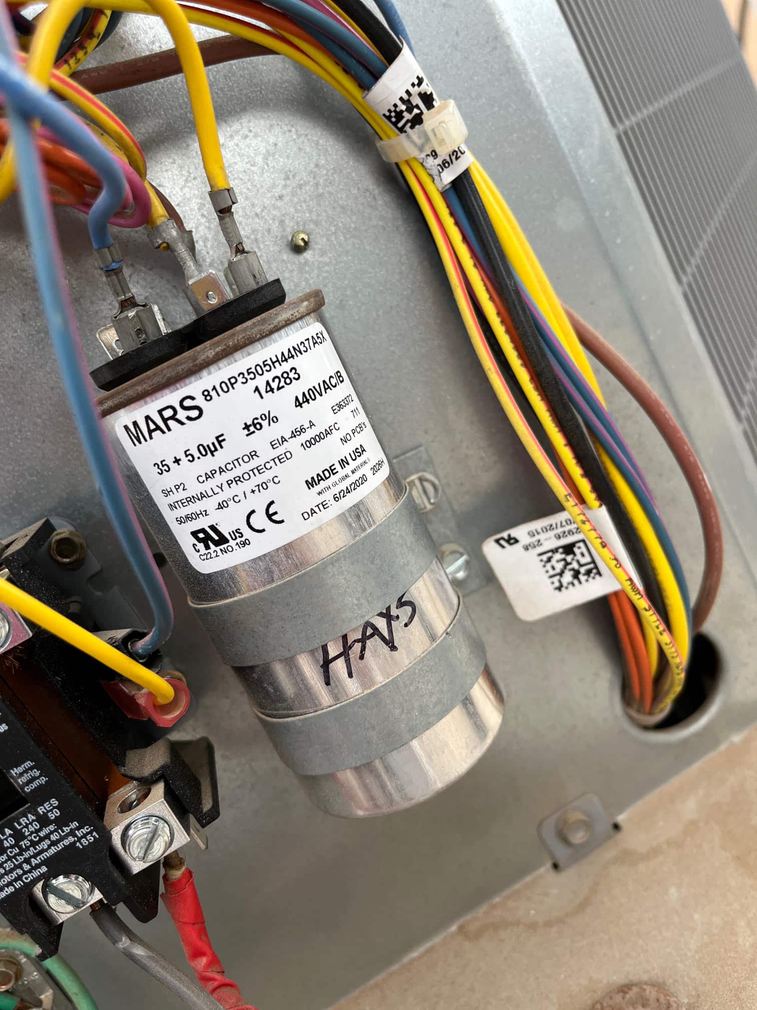 Dual-run capacitor labeled 35 + 5 μF, 440VAC, with wiring connected to its terminals inside the outdoor unit.