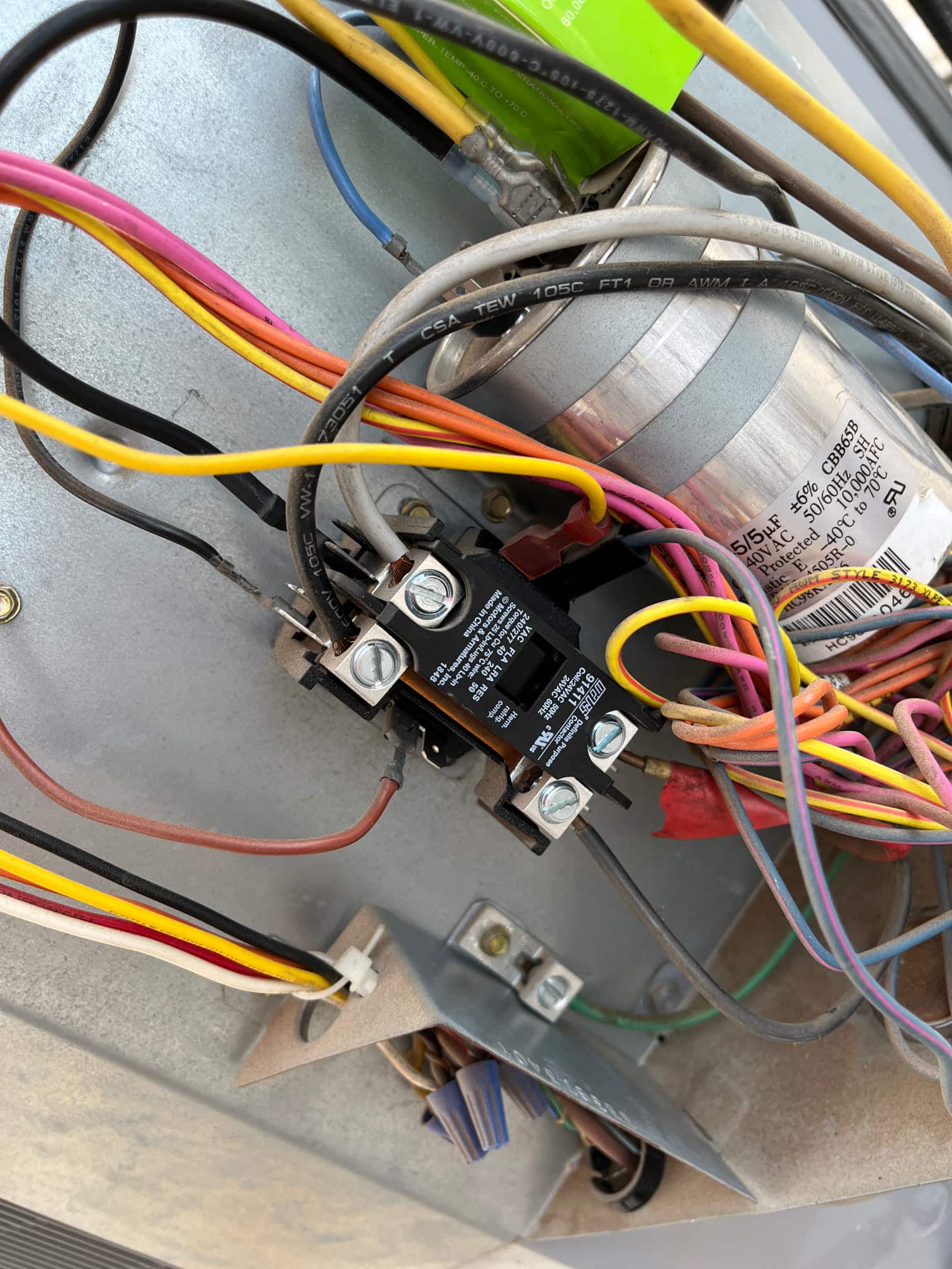 Dual-run capacitor labeled 45/5 μF and contactor with multiple color-coded wires inside the condenser panel.