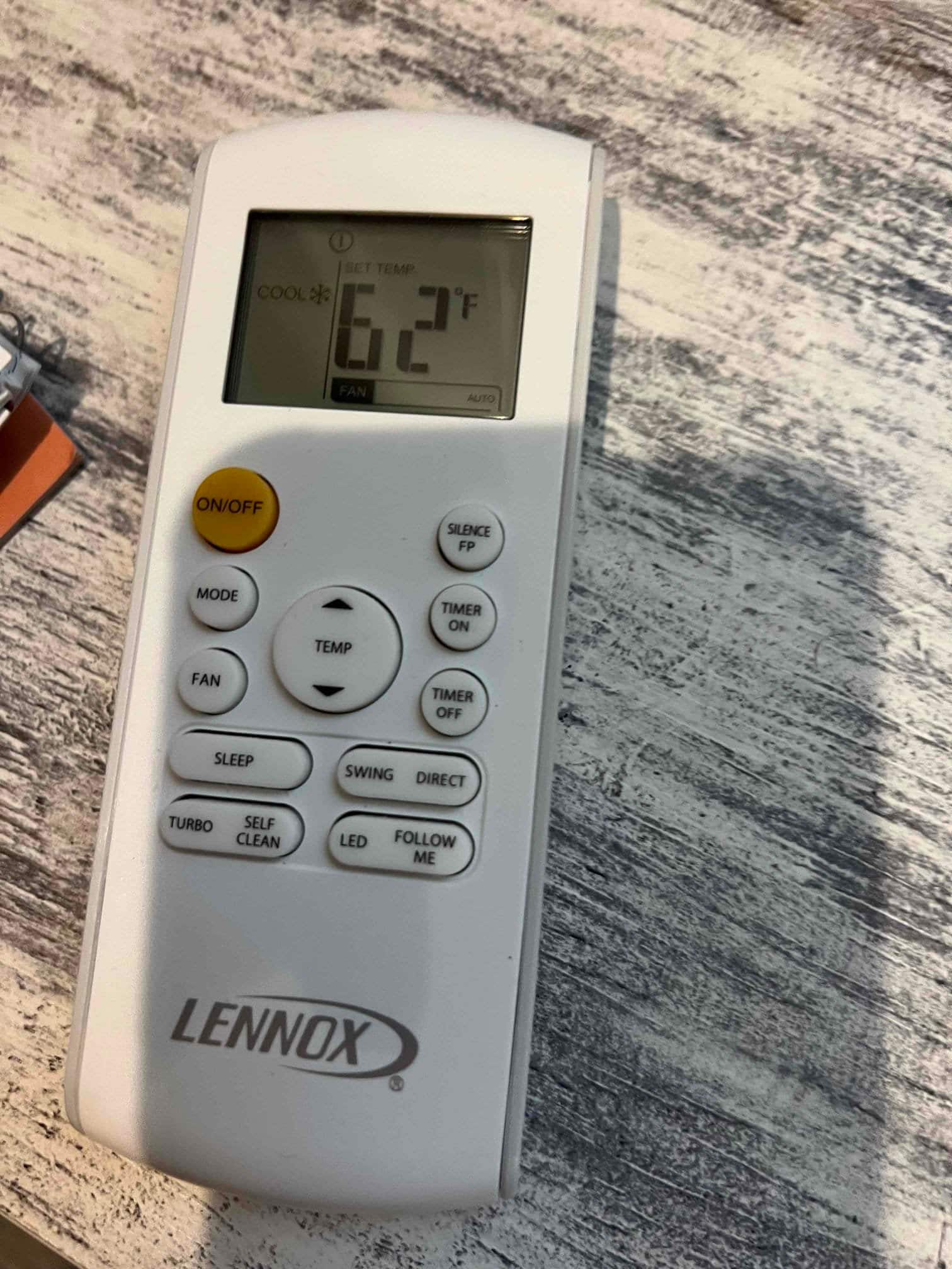 Handheld HVAC remote displays cooling mode with set temperature at 62°F and fan on auto.