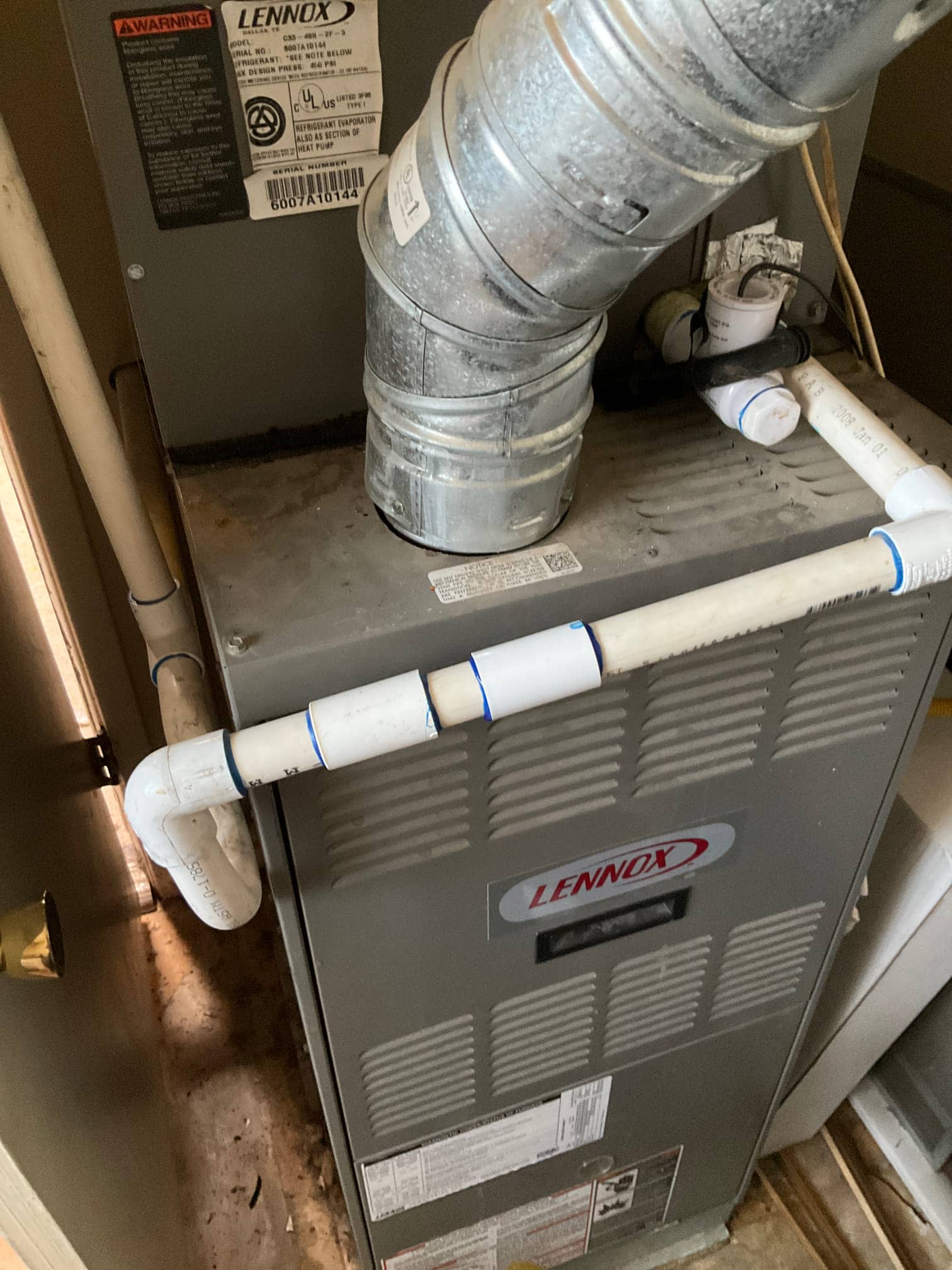 Indoor furnace cabinet with metal flue vent and PVC condensate drain piping visible at the service area.