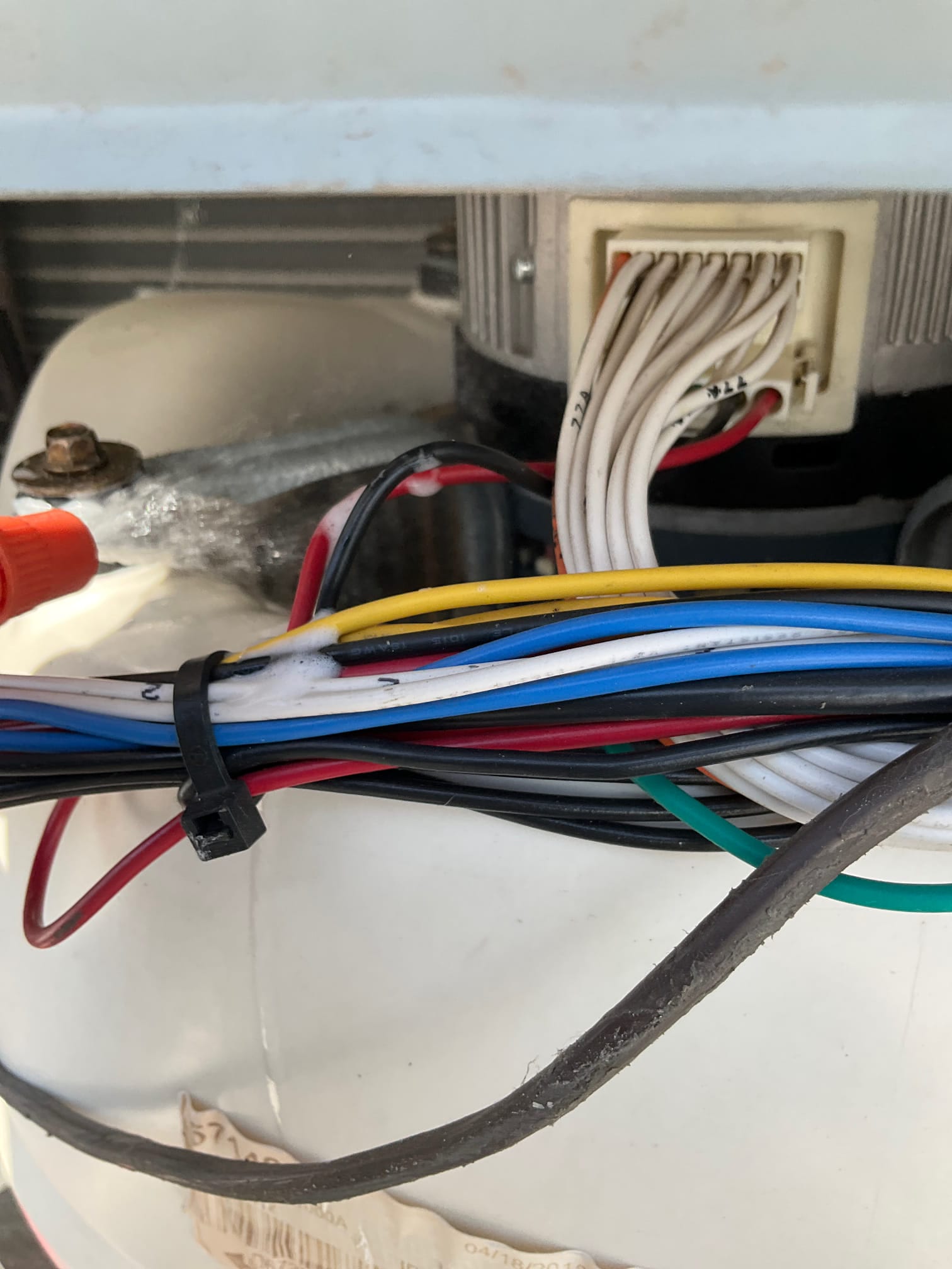 Motor terminal block with multiple white leads and bundled colored control wires secured by a zip tie.