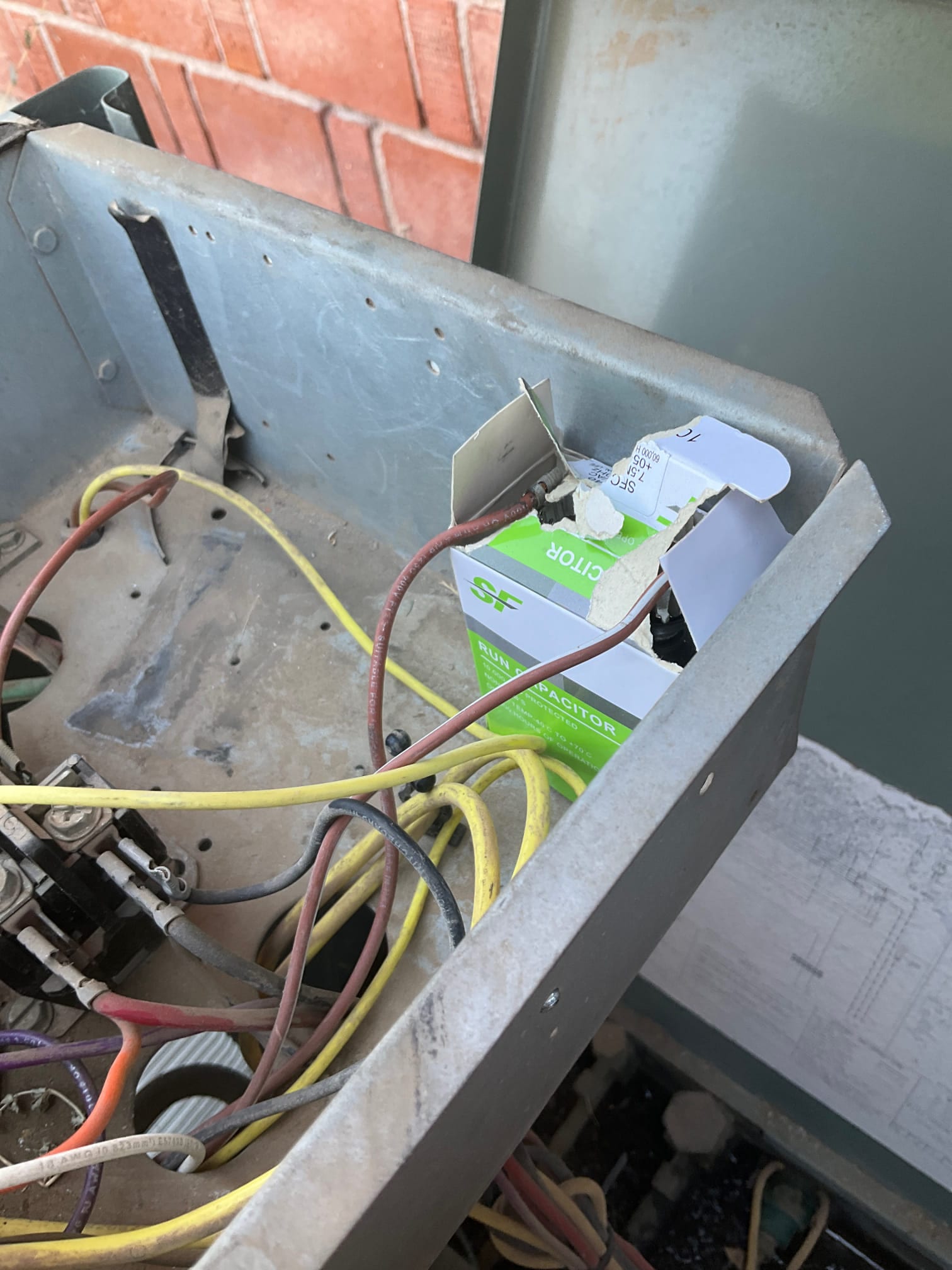 Open condenser control compartment with dusty wiring, contactor, and a boxed run capacitor beside the panel.