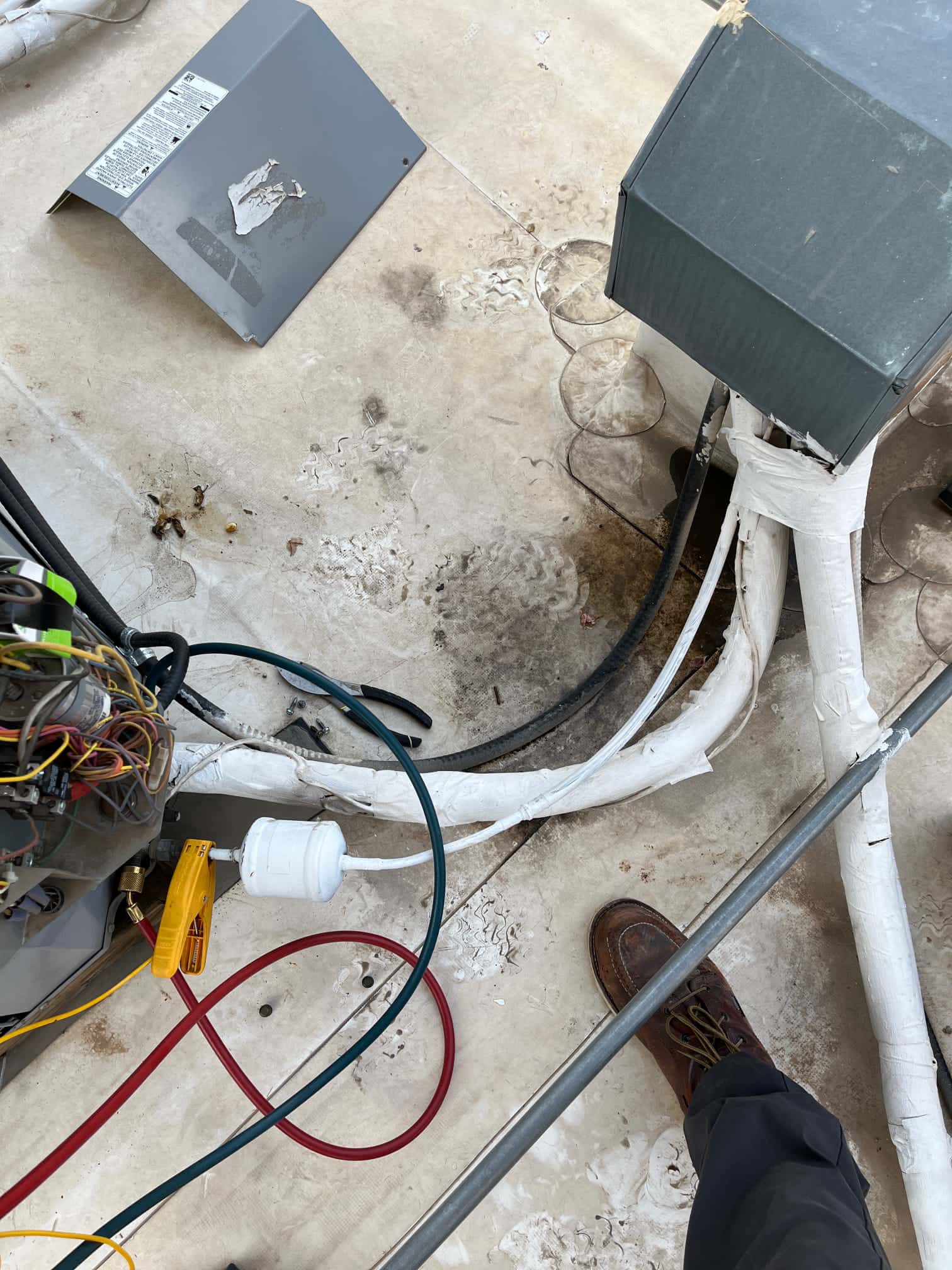 Open HVAC unit with wiring exposed, insulated refrigerant lines, and red and green service hoses attached.