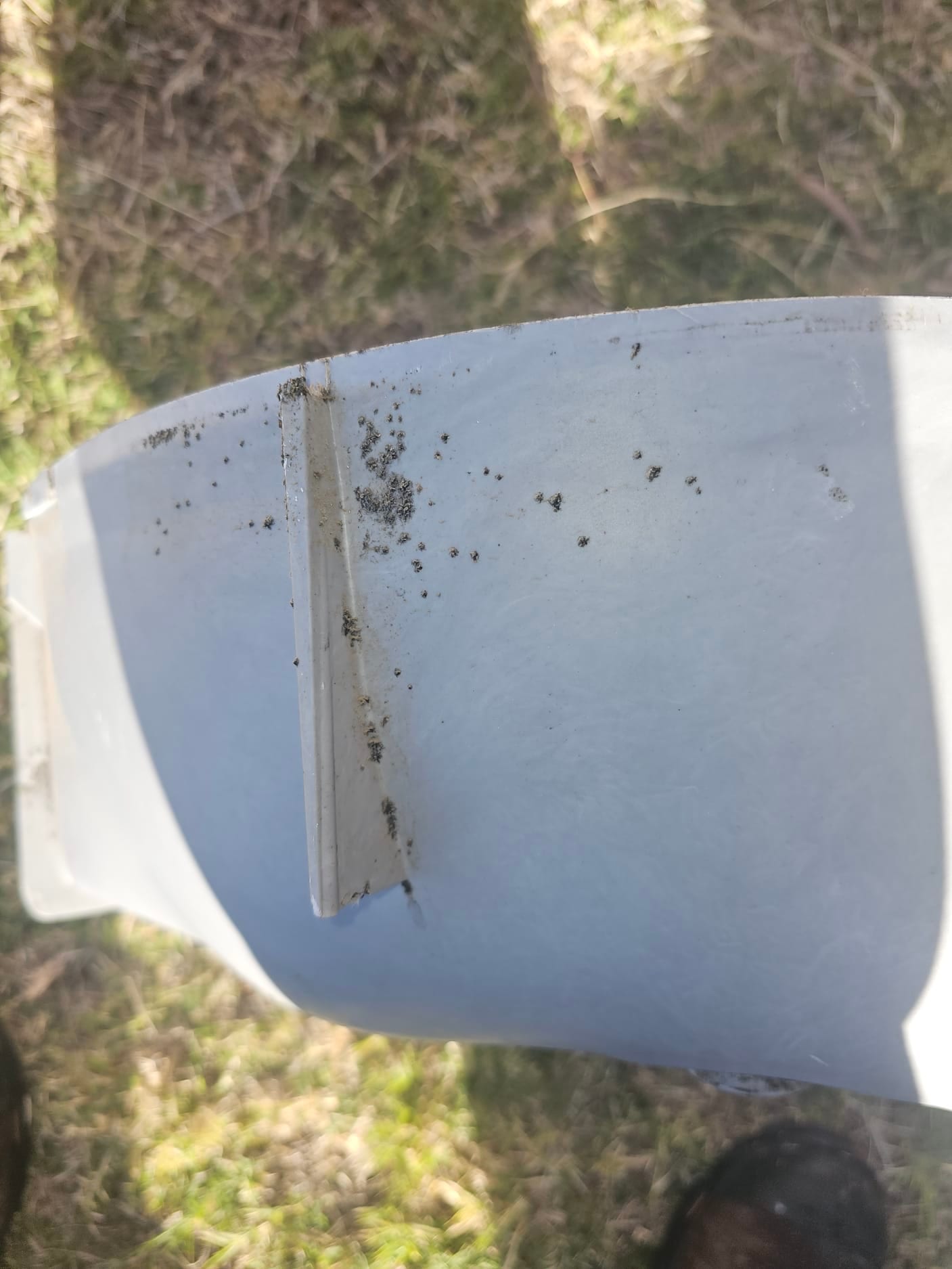 Plastic fan blade with a reinforcement rib and scattered dirt deposits on the surface.