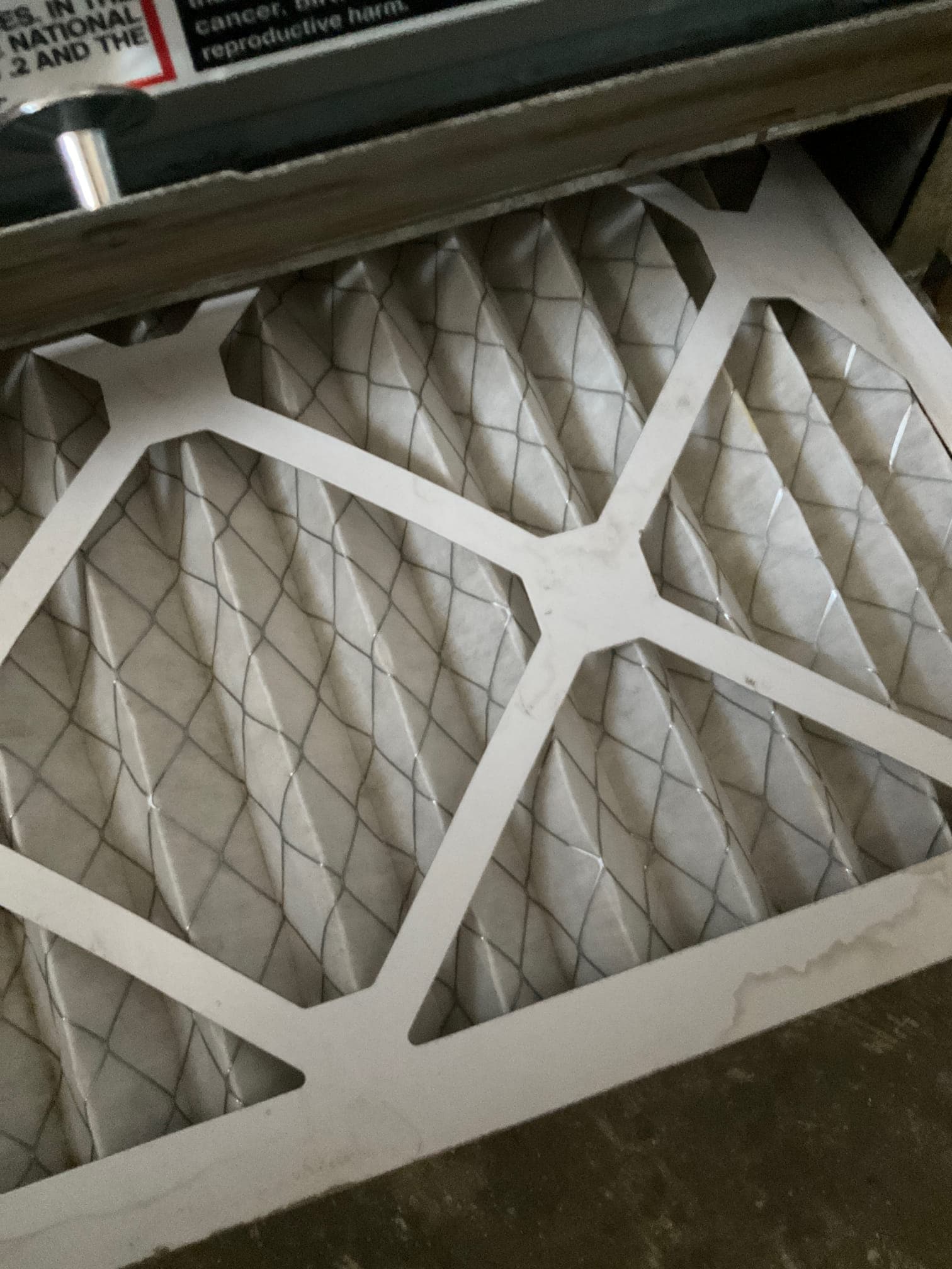 Pleated HVAC air filter installed in a filter rack at the indoor unit.