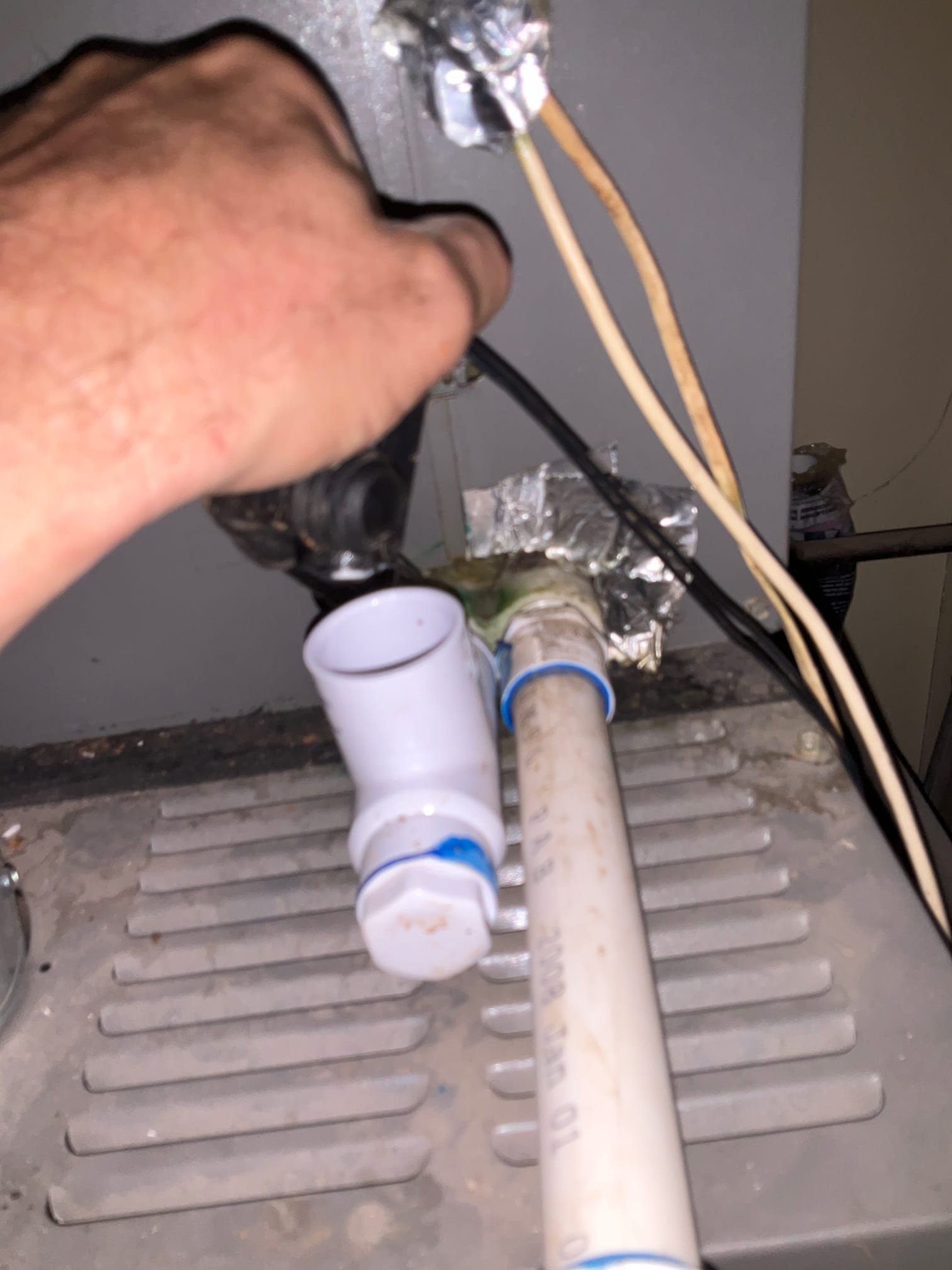 PVC condensate drain piping with cleanout tee and caps on the air handler cabinet.