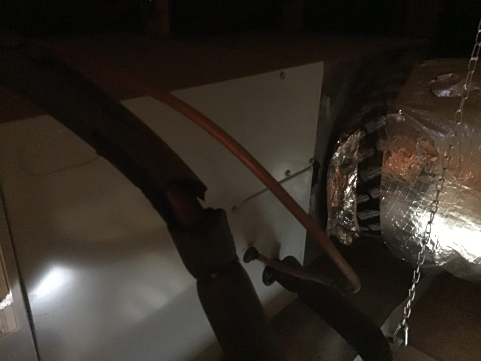 Refrigerant lineset enters the air handler cabinet; black insulation is split, with flexible duct connection visible nearby.
