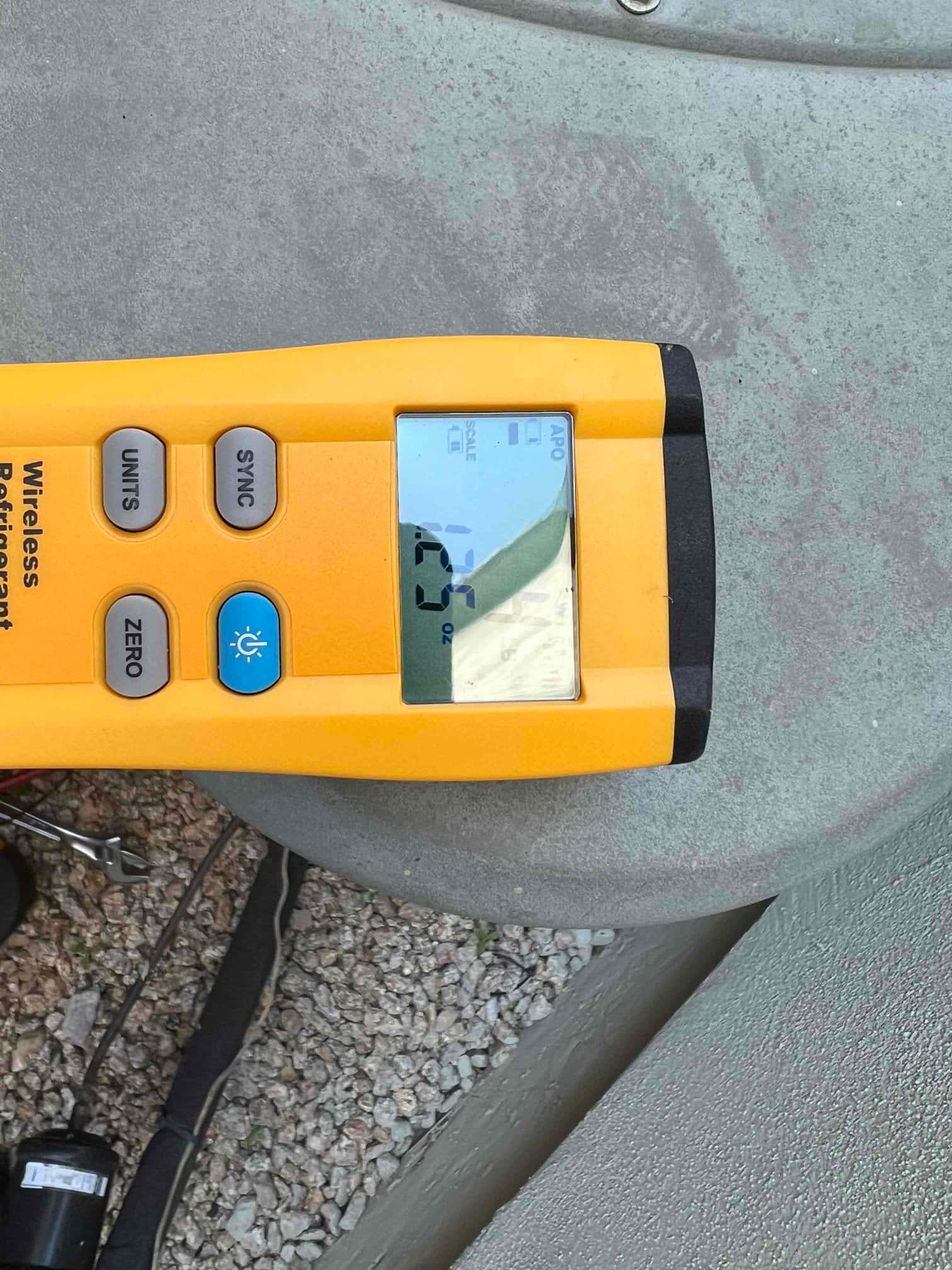 Refrigerant scale photographed during the service visit; no numerical reading is transcribed.