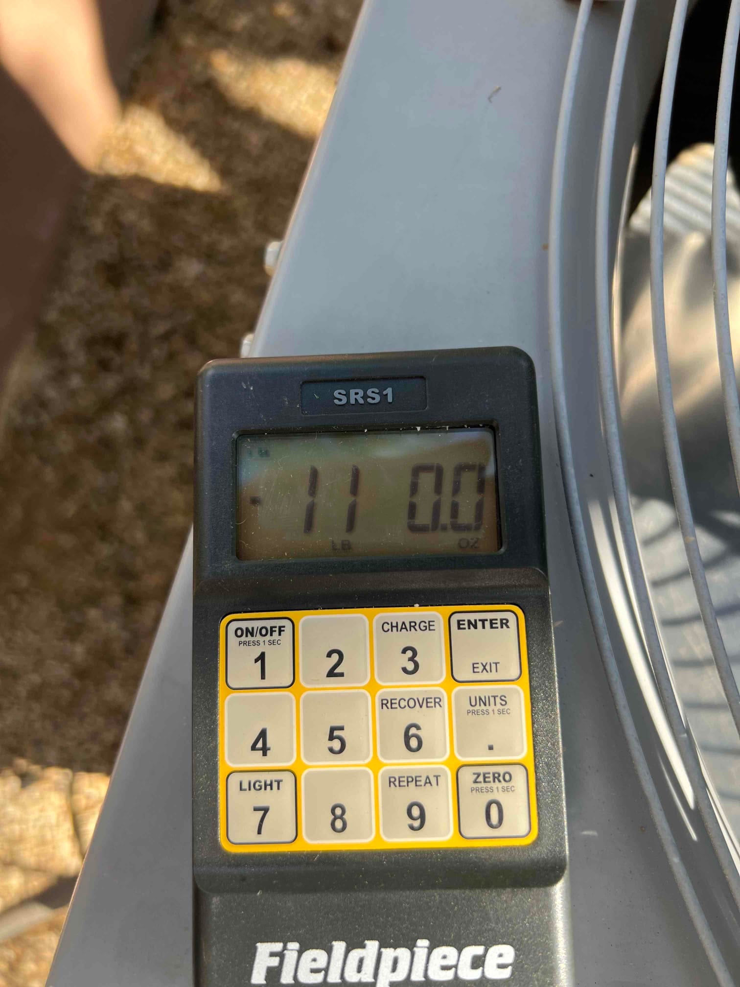 Refrigerant scale photographed during the service visit; no numerical reading is transcribed.