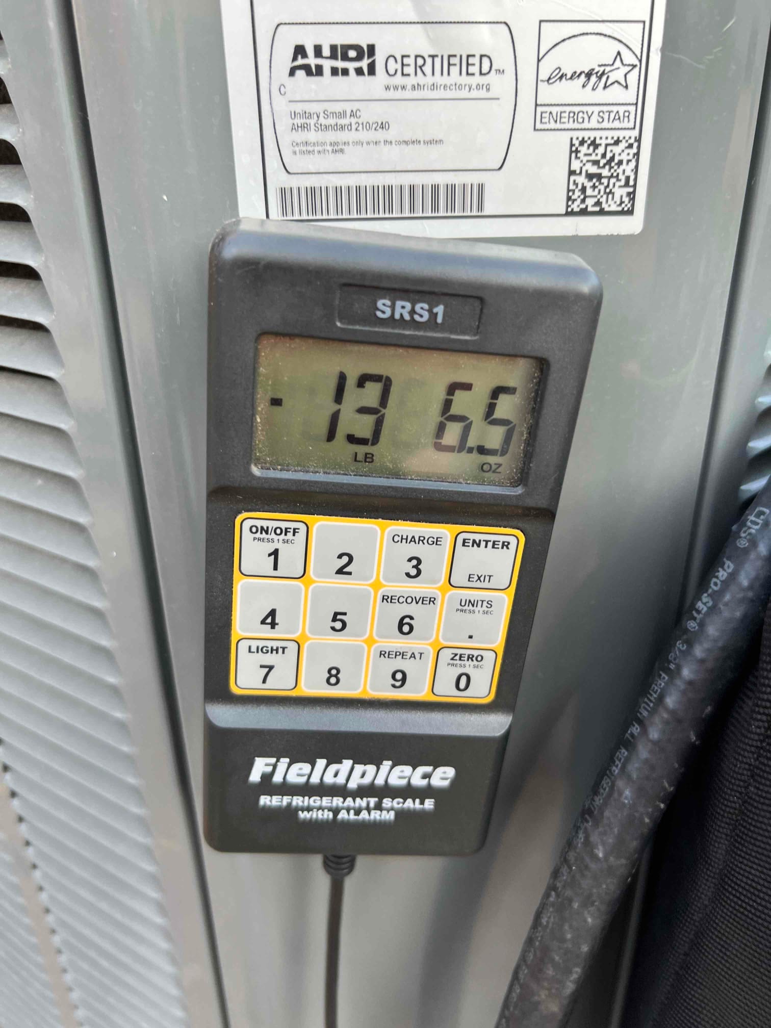 Refrigerant scale photographed during the service visit; no numerical reading is transcribed.