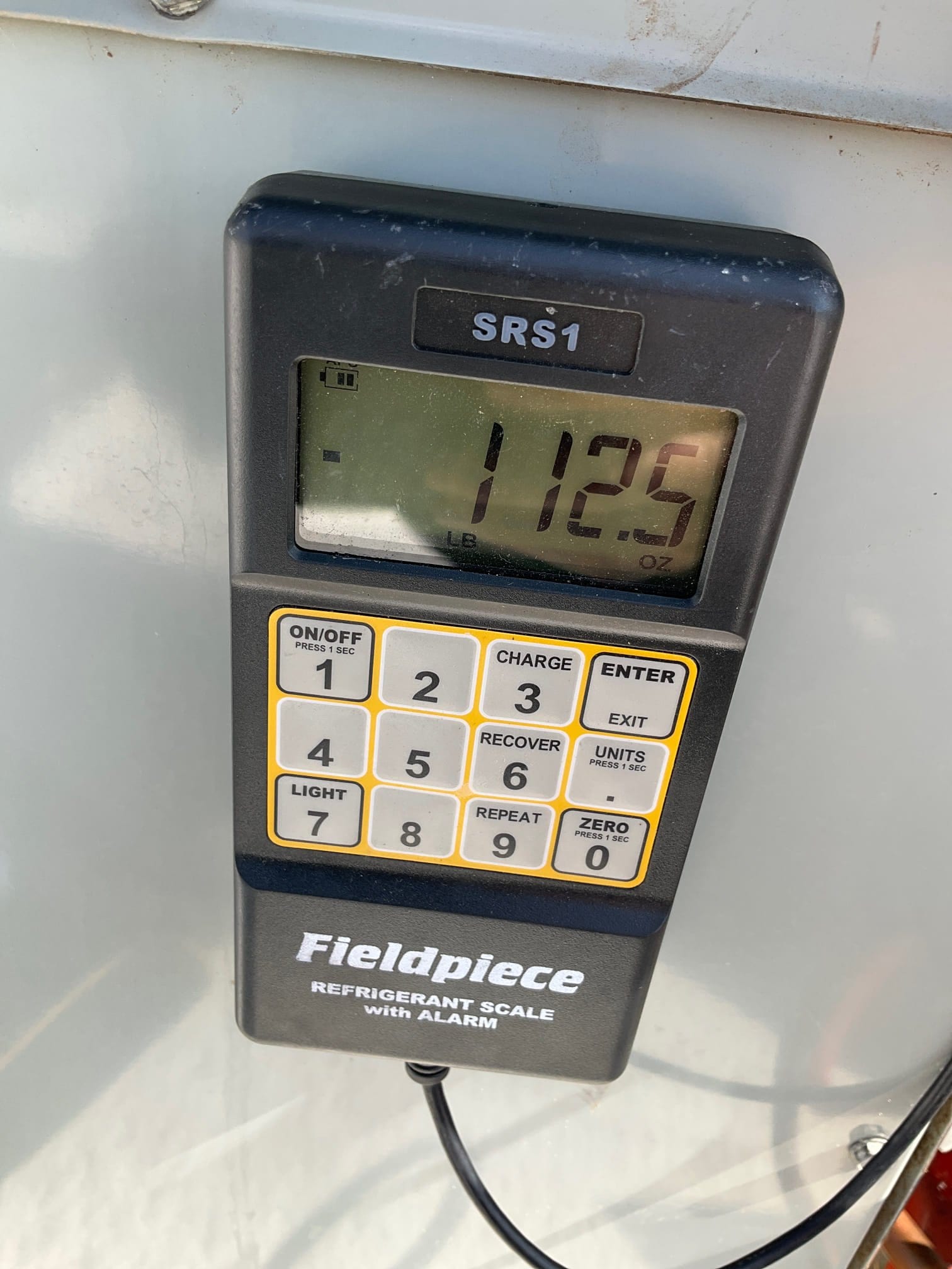 Refrigerant scale photographed during the service visit; no numerical reading is transcribed.