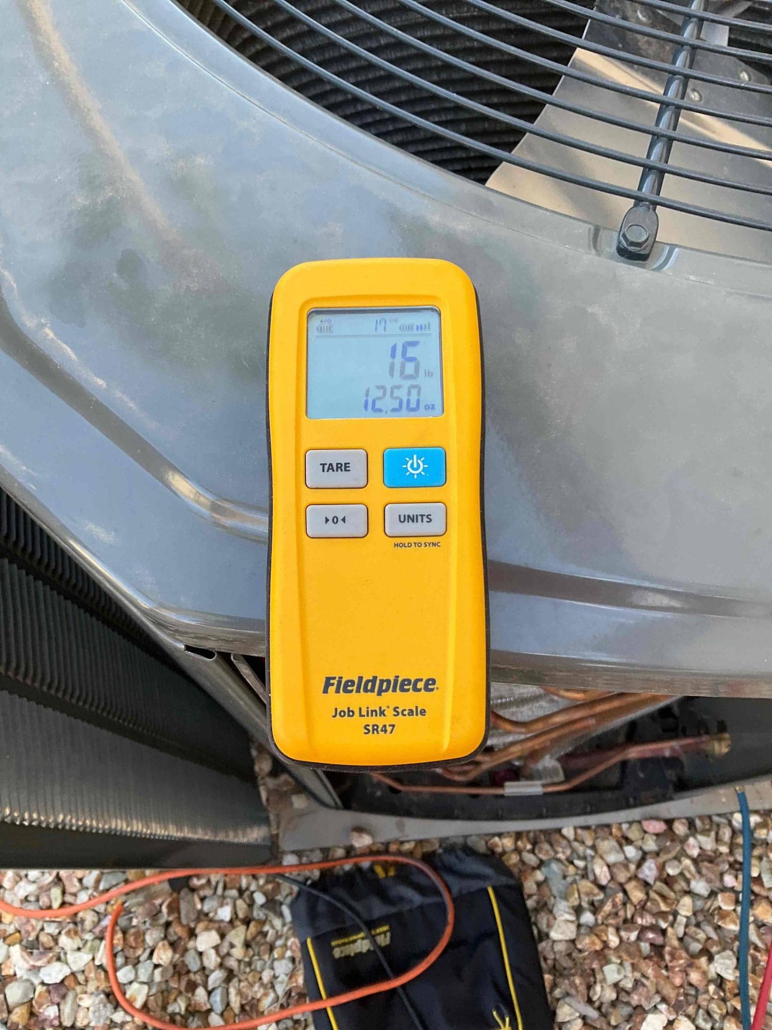 Refrigerant scale photographed during the service visit; no numerical reading is transcribed.
