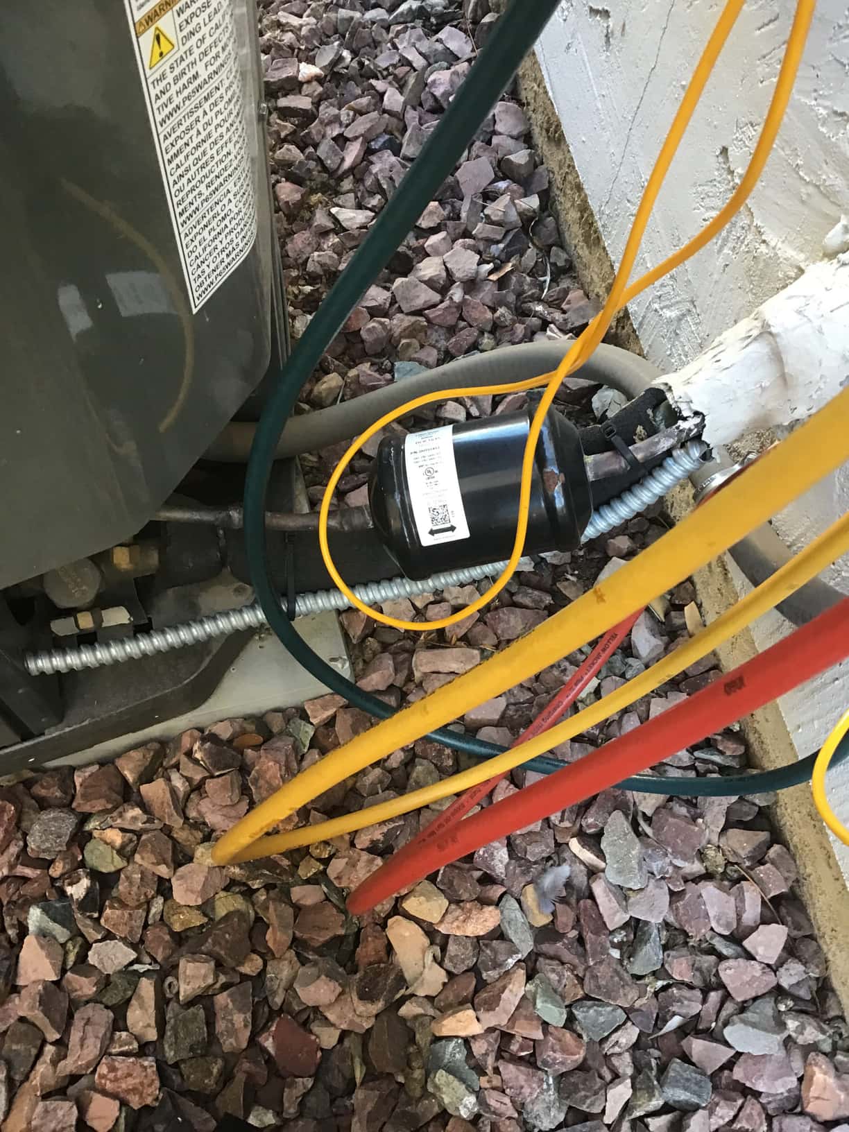 Refrigerant service hoses attached near the outdoor unit, showing an inline black cylinder on the refrigeration line.