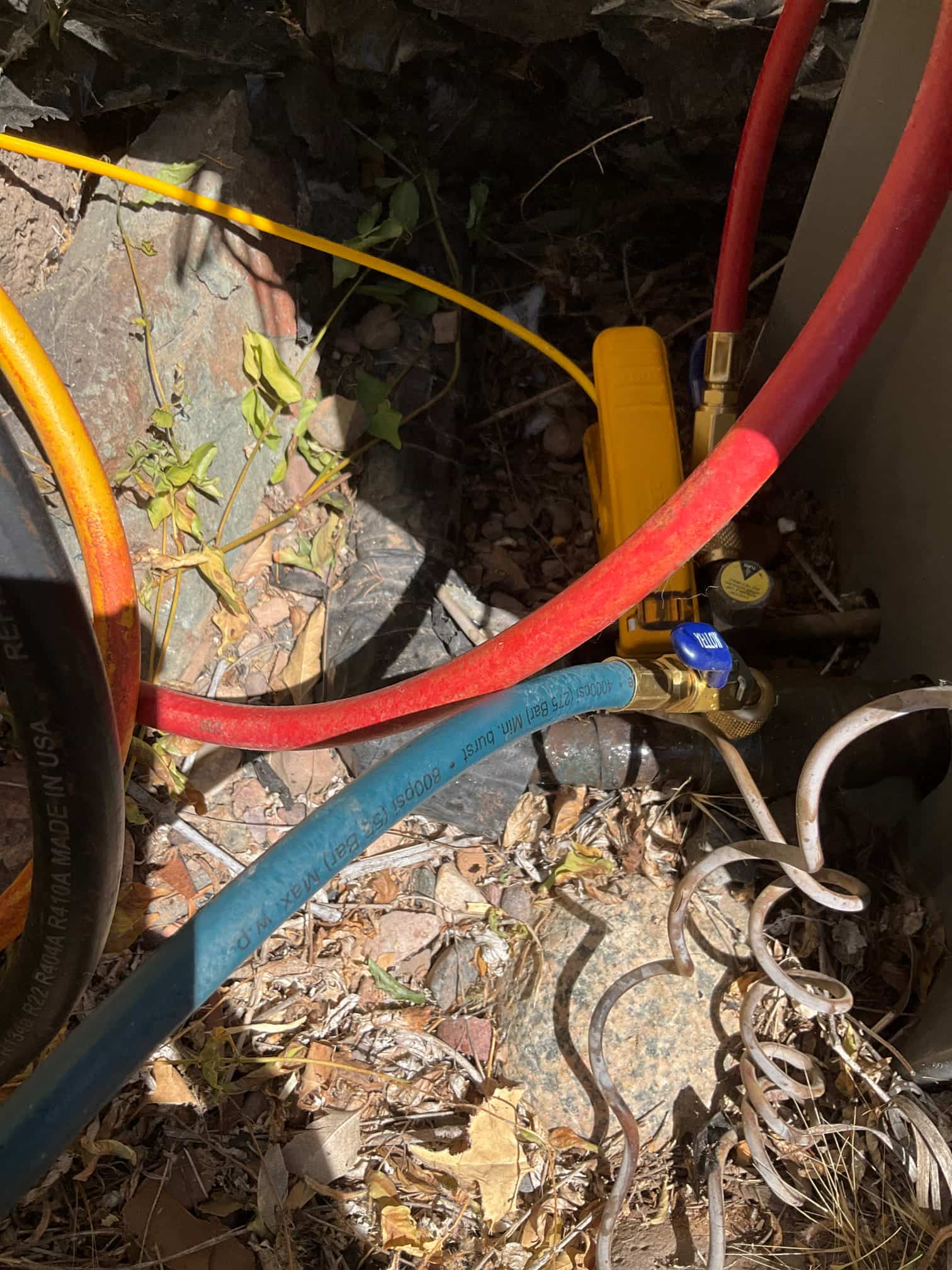 Refrigerant service hoses with shutoff valve attached to the outdoor condenser service port next to the unit.