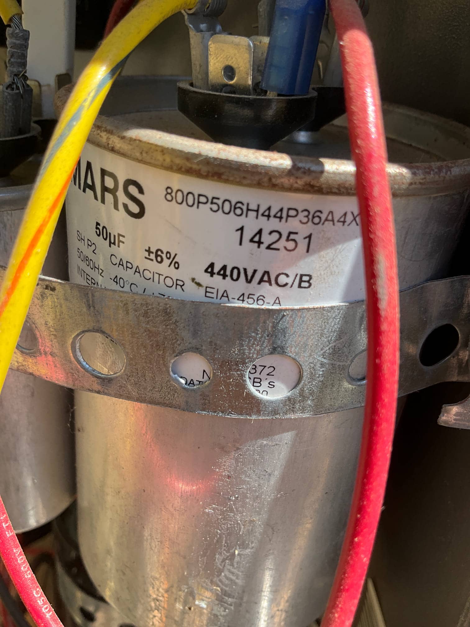Run capacitor labeled 50 μF ±6% and 440VAC, secured in a bracket, with yellow, blue, and red wires connected to terminals.