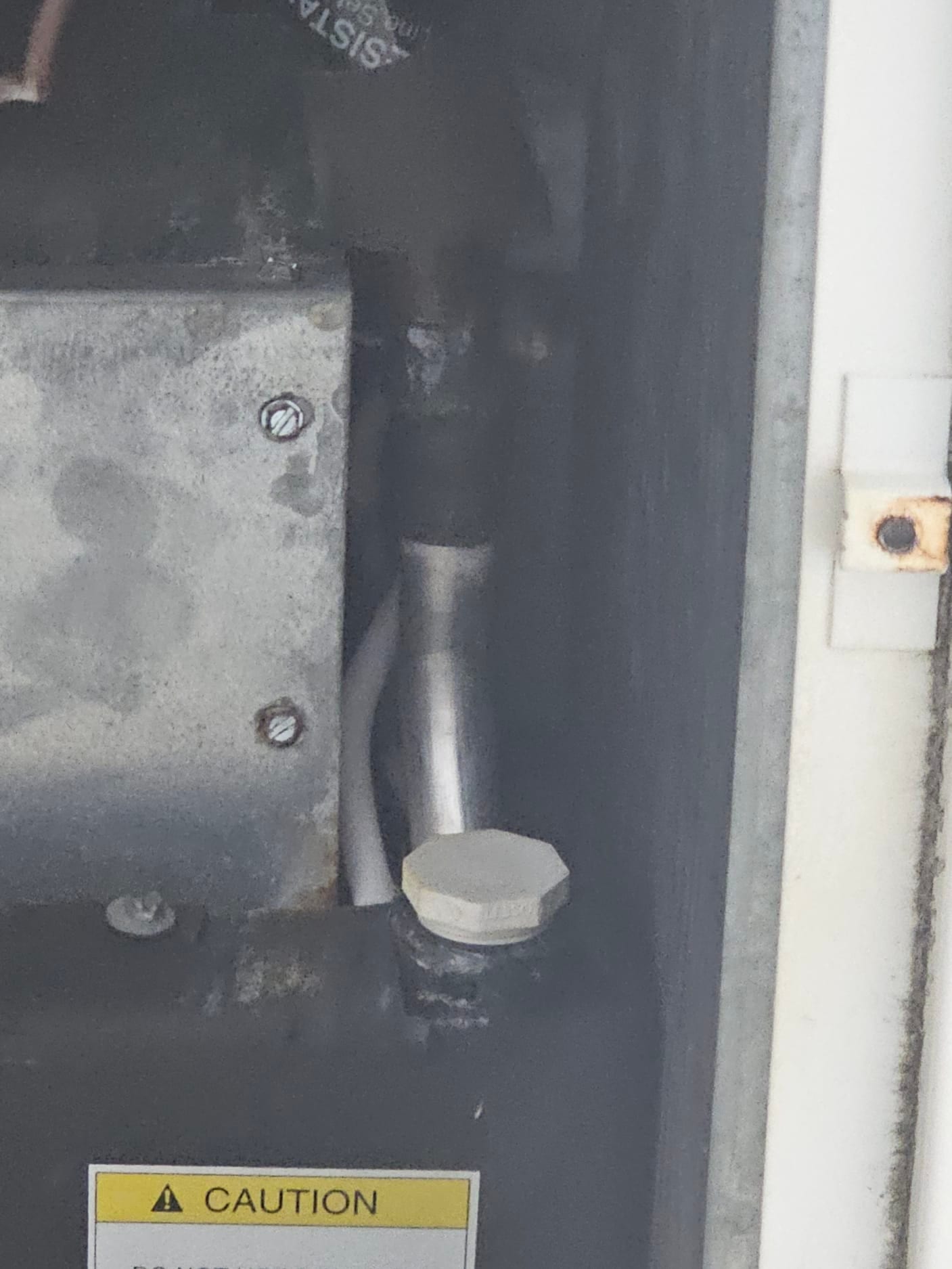 Service valve with hex cap and connected refrigerant line inside the outdoor condenser cabinet.