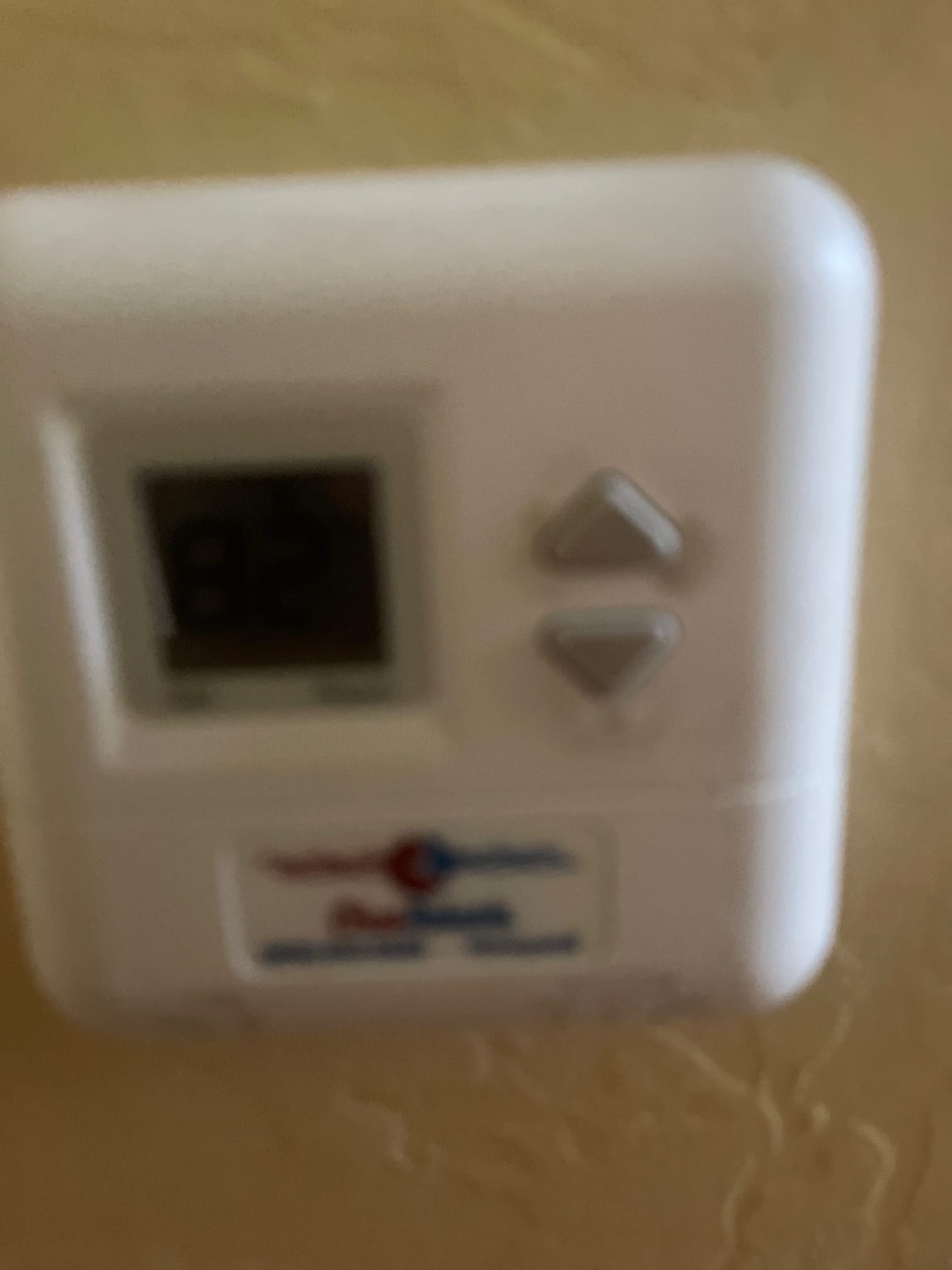 Wall-mounted digital thermostat showing 82 on the display with up and down buttons.