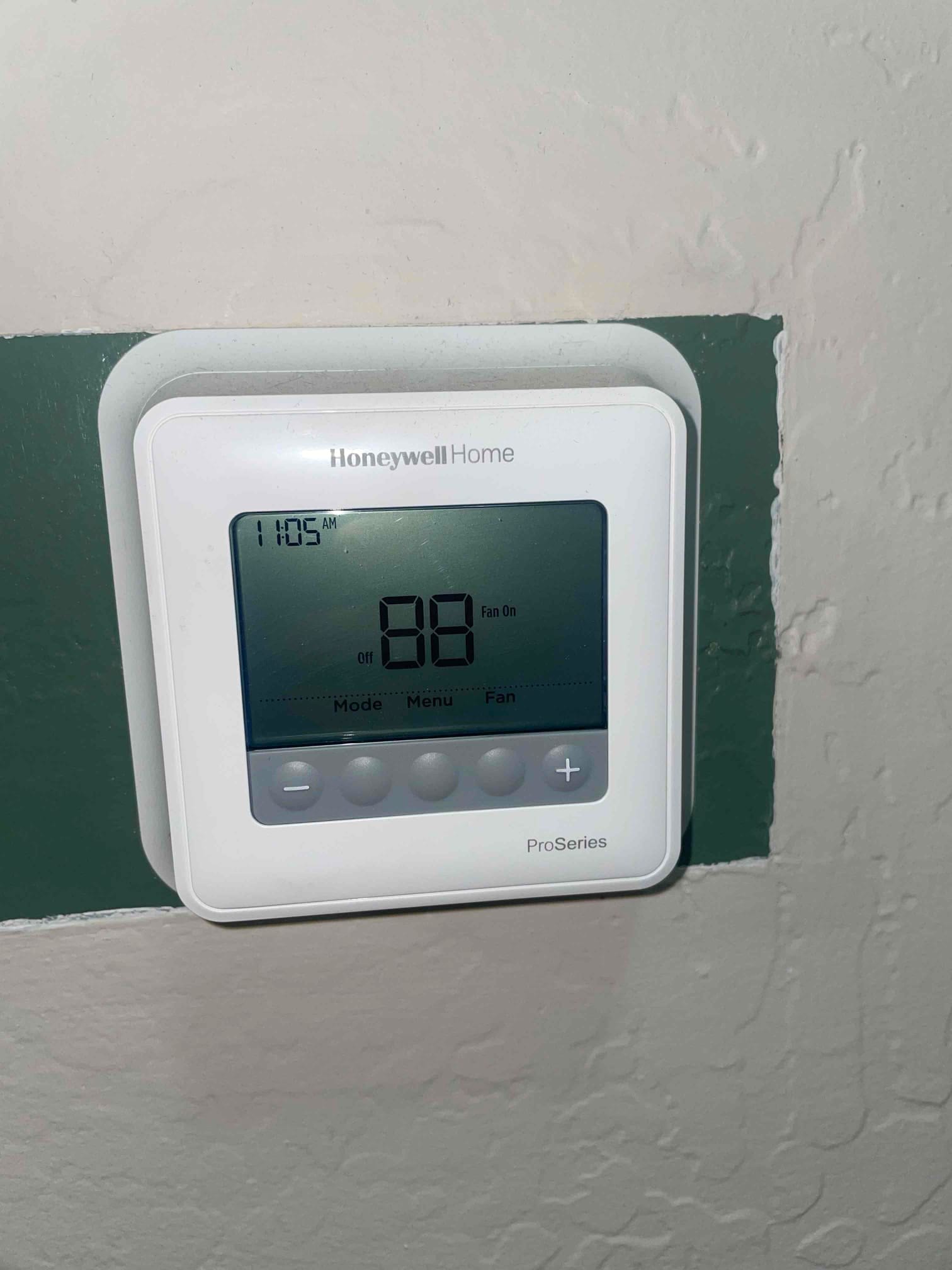 Wall-mounted digital thermostat displays 11:05 AM, system off, and fan on indicator illuminated.