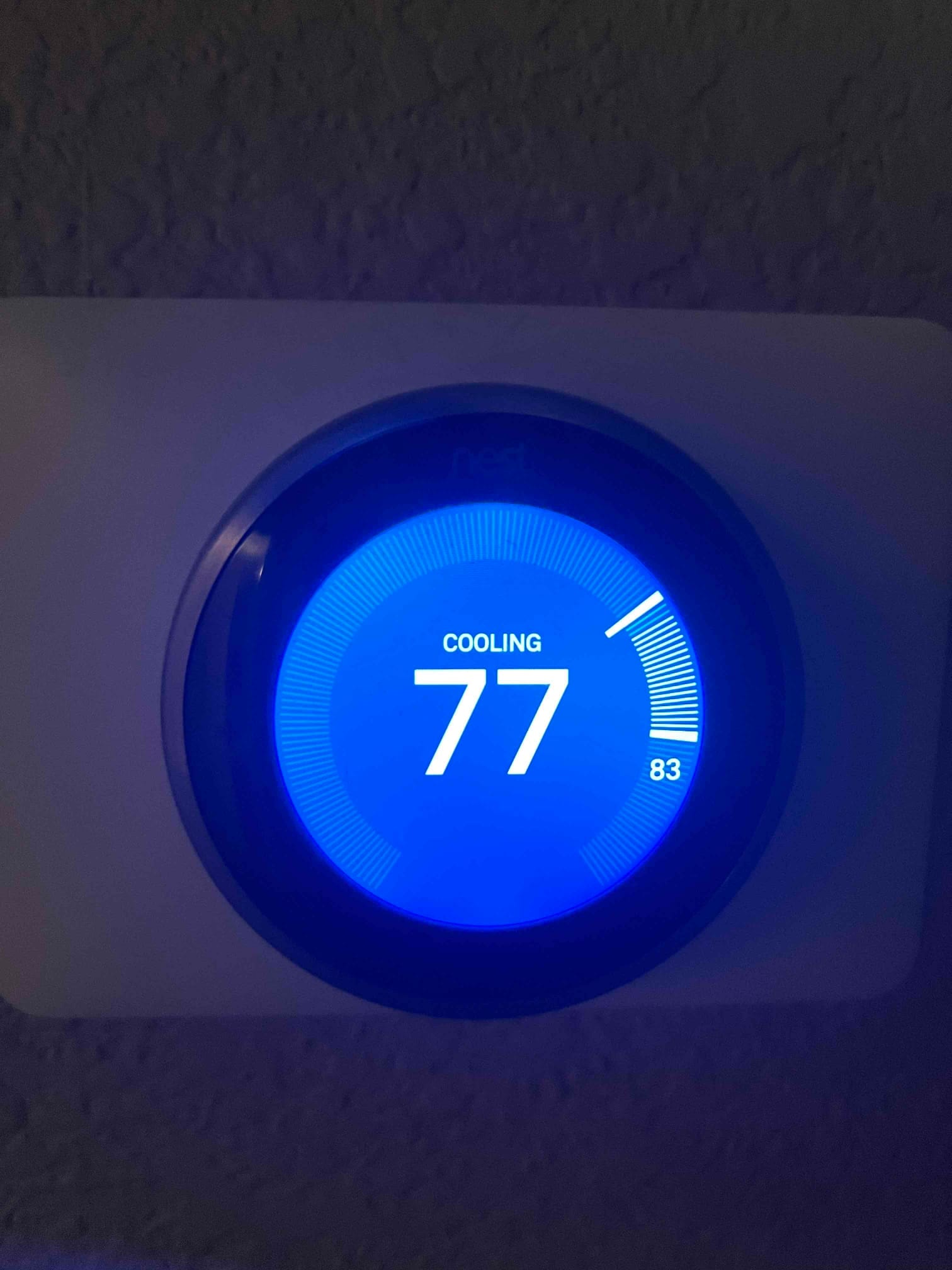 Wall-mounted smart thermostat is active in Cooling mode, displaying 77 and an outer ring marker near 83.