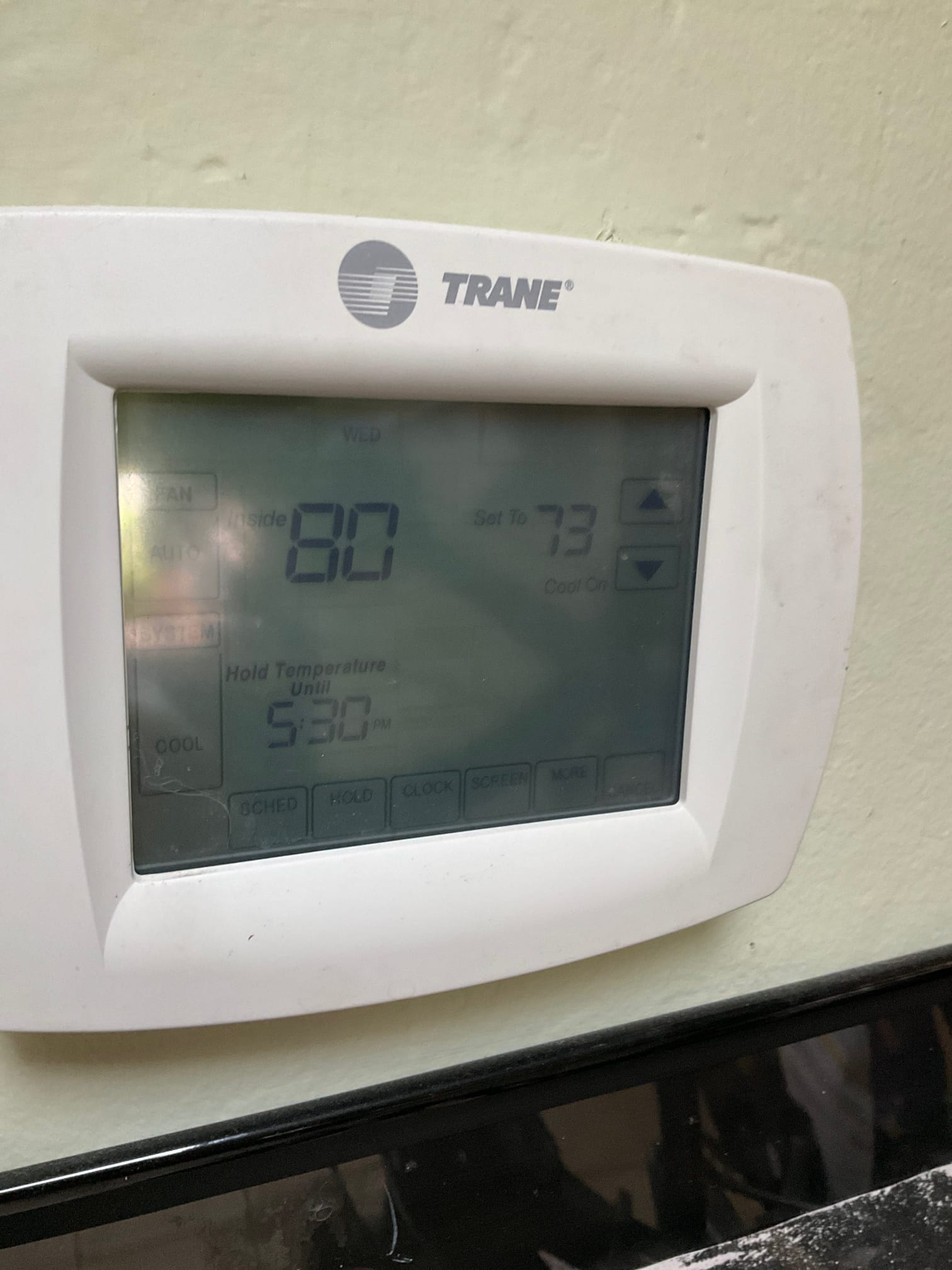 Wall-mounted thermostat display showing inside 80 and set to 73, cool mode, hold until 5:30 PM.