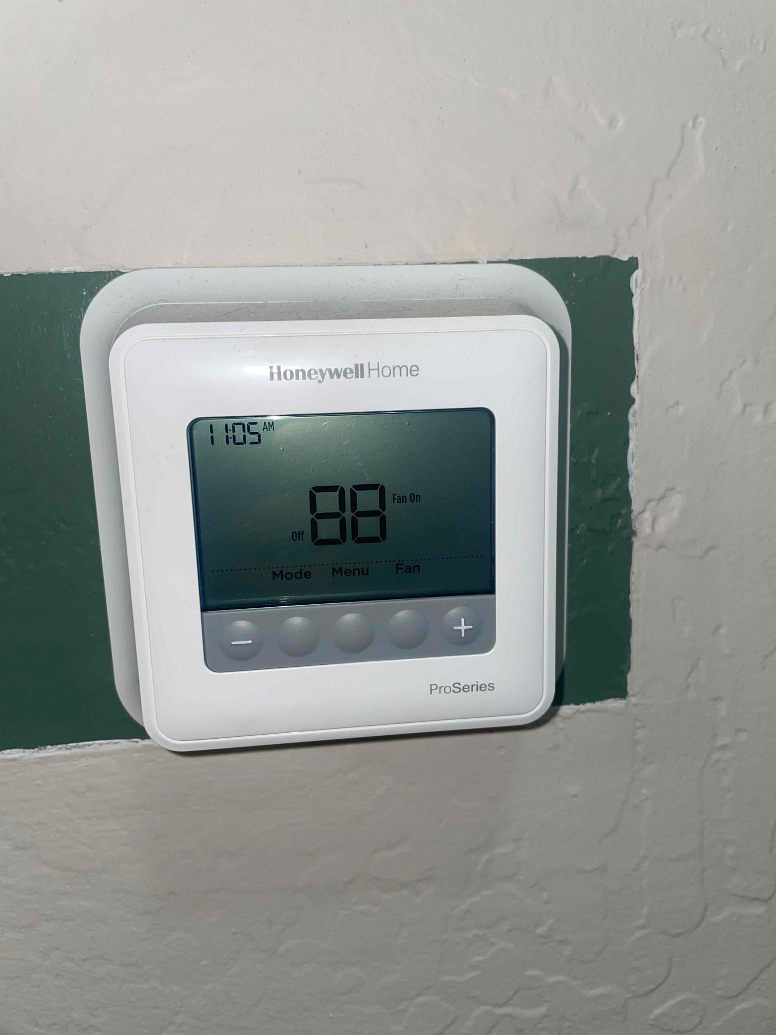 Wall-mounted thermostat display shows 11:05 AM with large numeric readout and an active fan indicator.