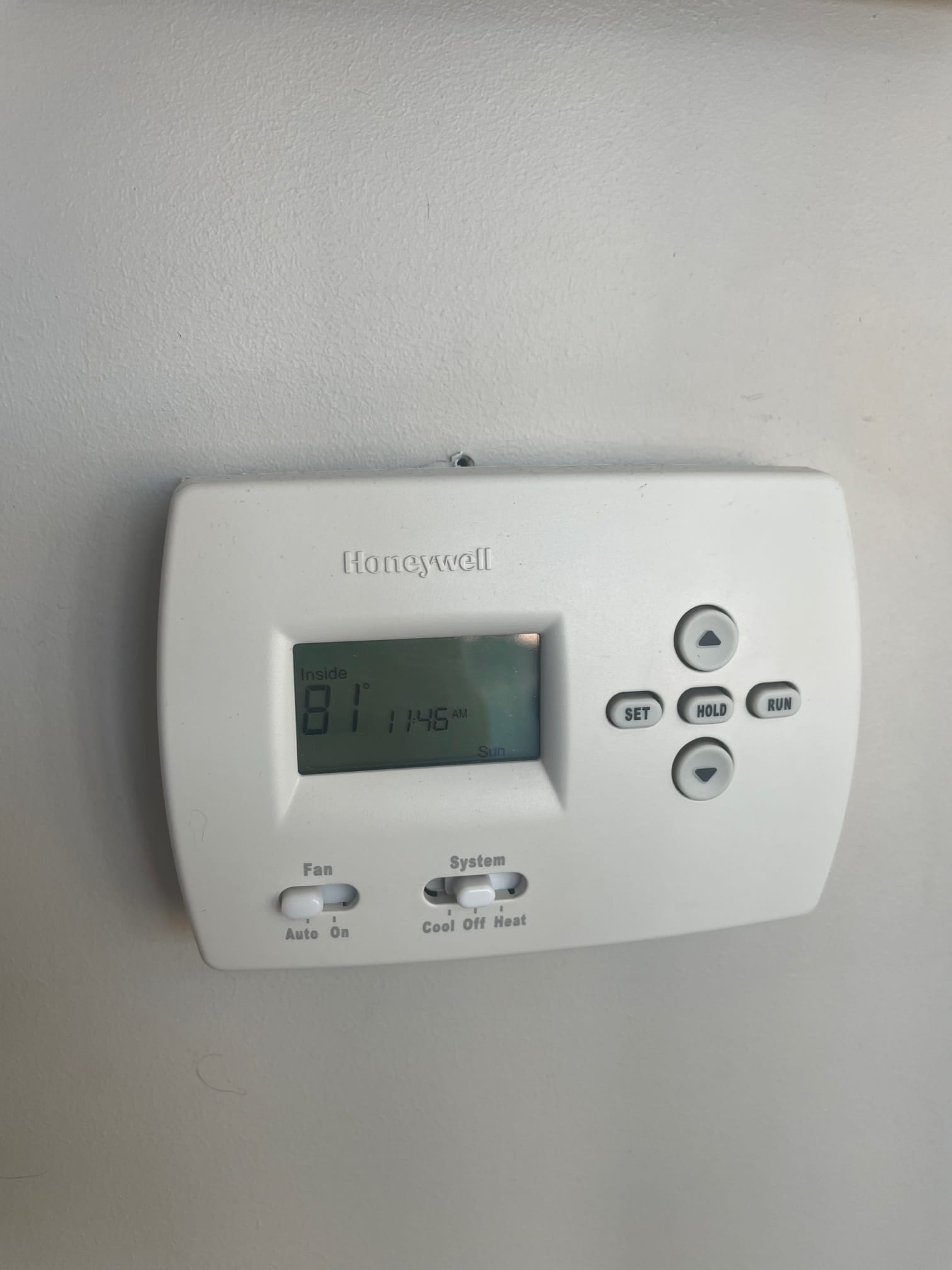 Wall-mounted thermostat shows inside temperature of 81 on the display with system and fan selector switches.