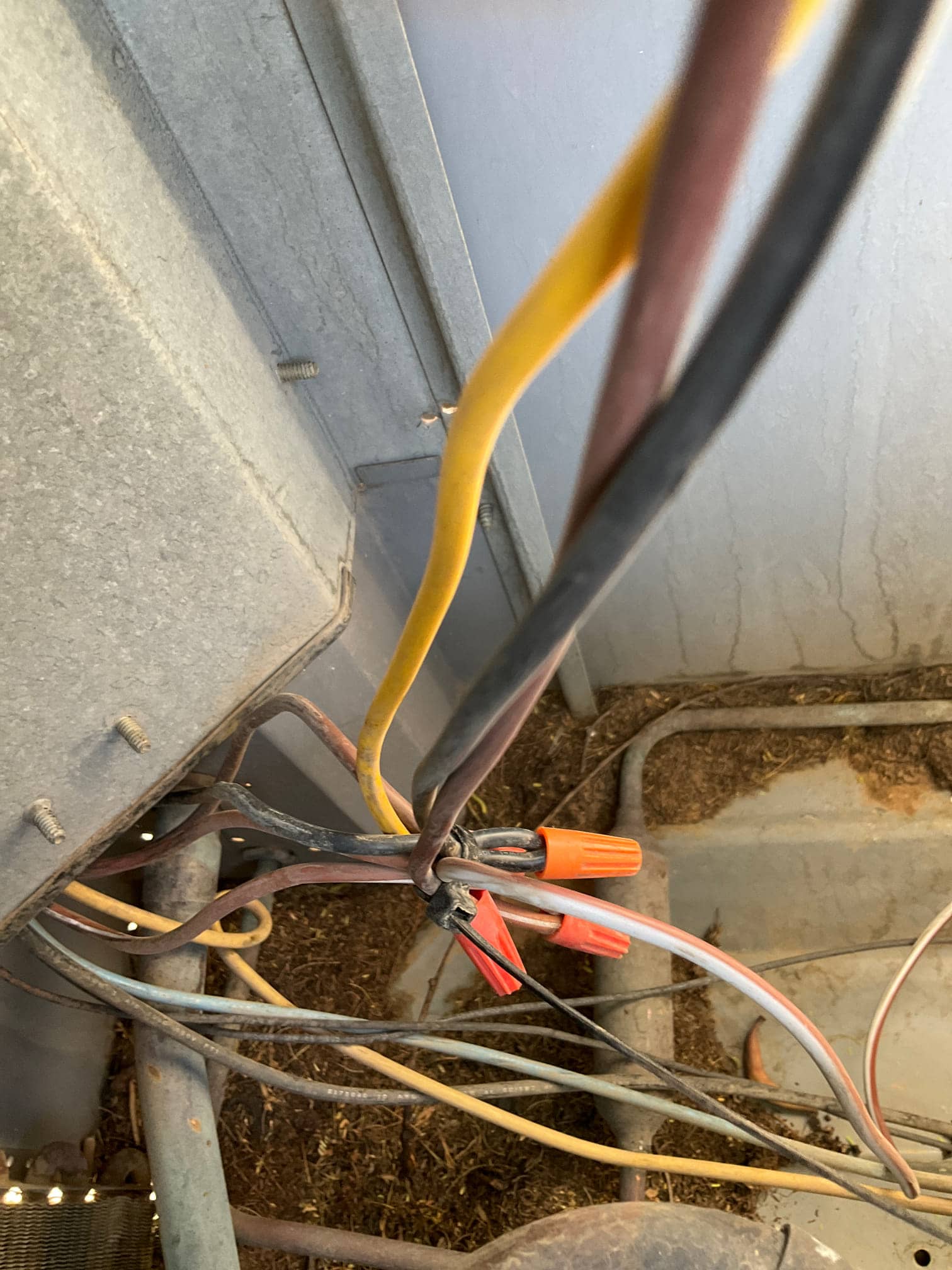 Wiring connections secured with orange wire nuts inside the condenser cabinet, with multiple colored conductors routed through the unit.