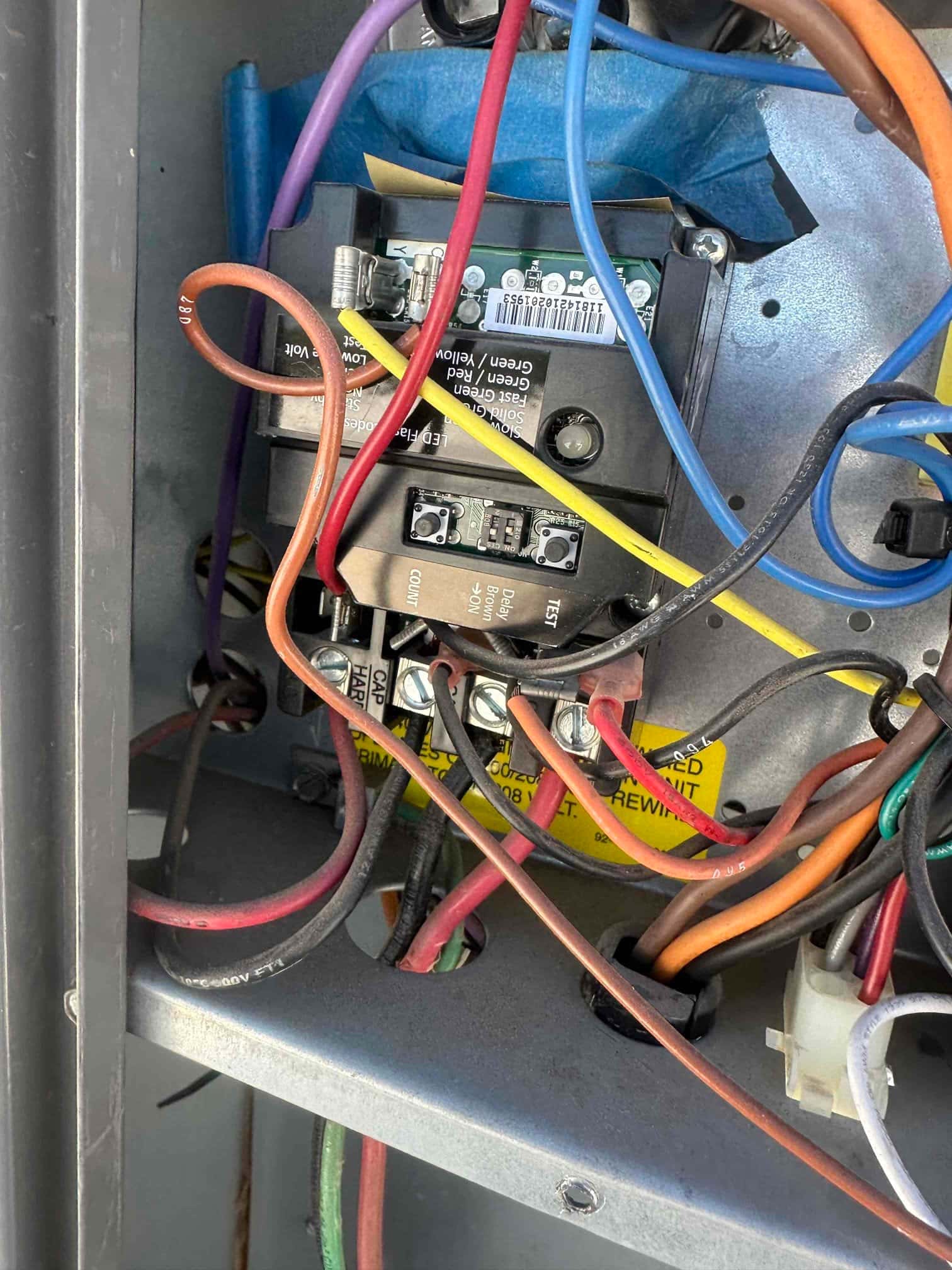 Air handler control compartment showing contactor and wiring, with labeled terminals and multiple colored conductors connected to screw terminals.